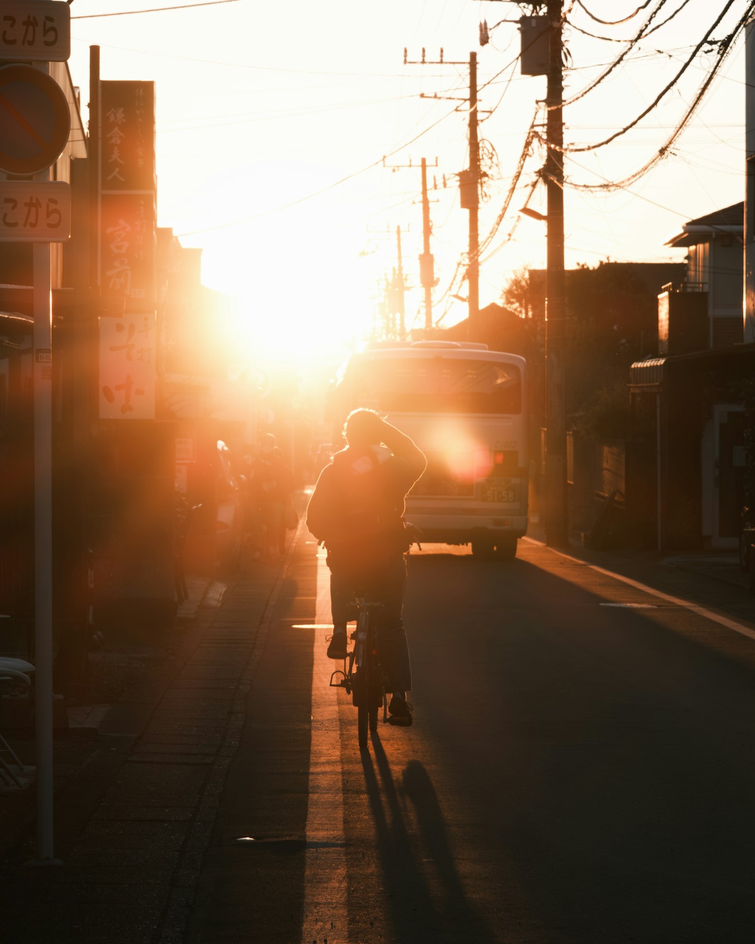 Silhouette d'une personne à vélo contre un coucher de soleil avec une scène de rue