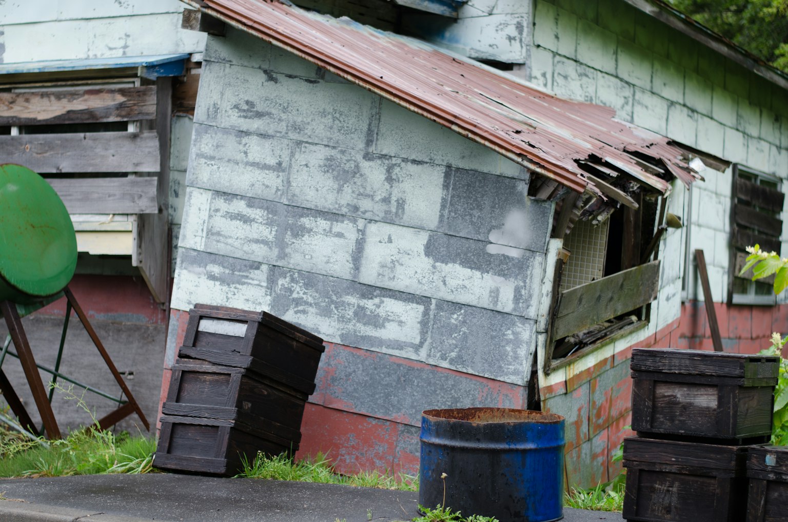 Rumah tua miring dengan puing-puing di sekitarnya