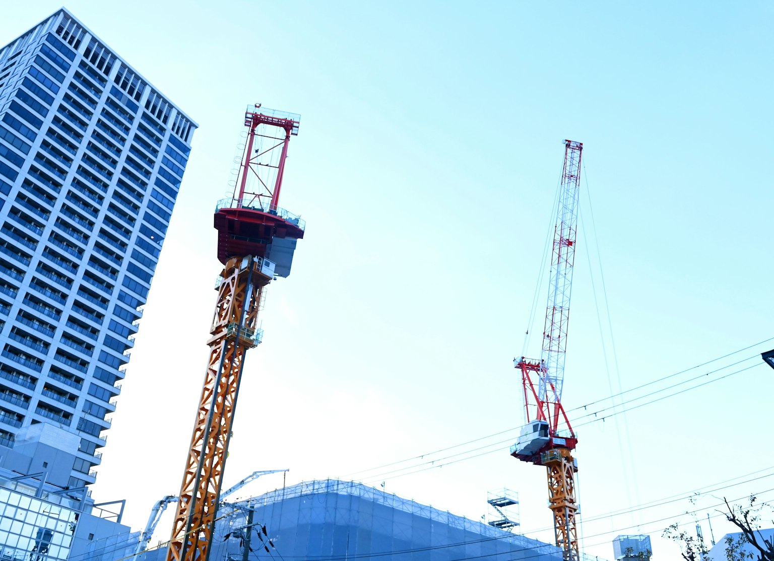 Cranes at a high-rise construction site with a clear blue sky