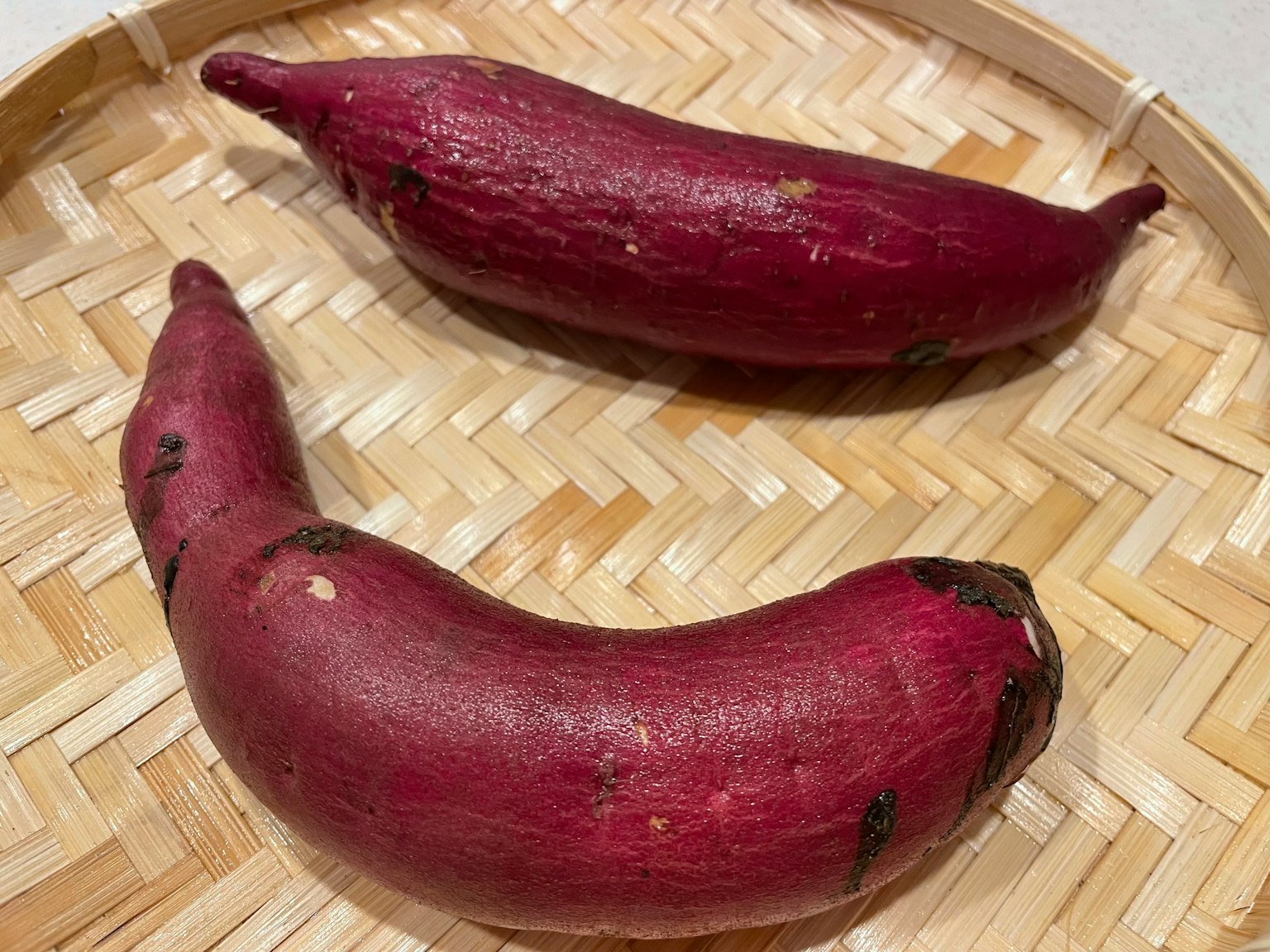 Dos batatas moradas en una bandeja de bambú tejida