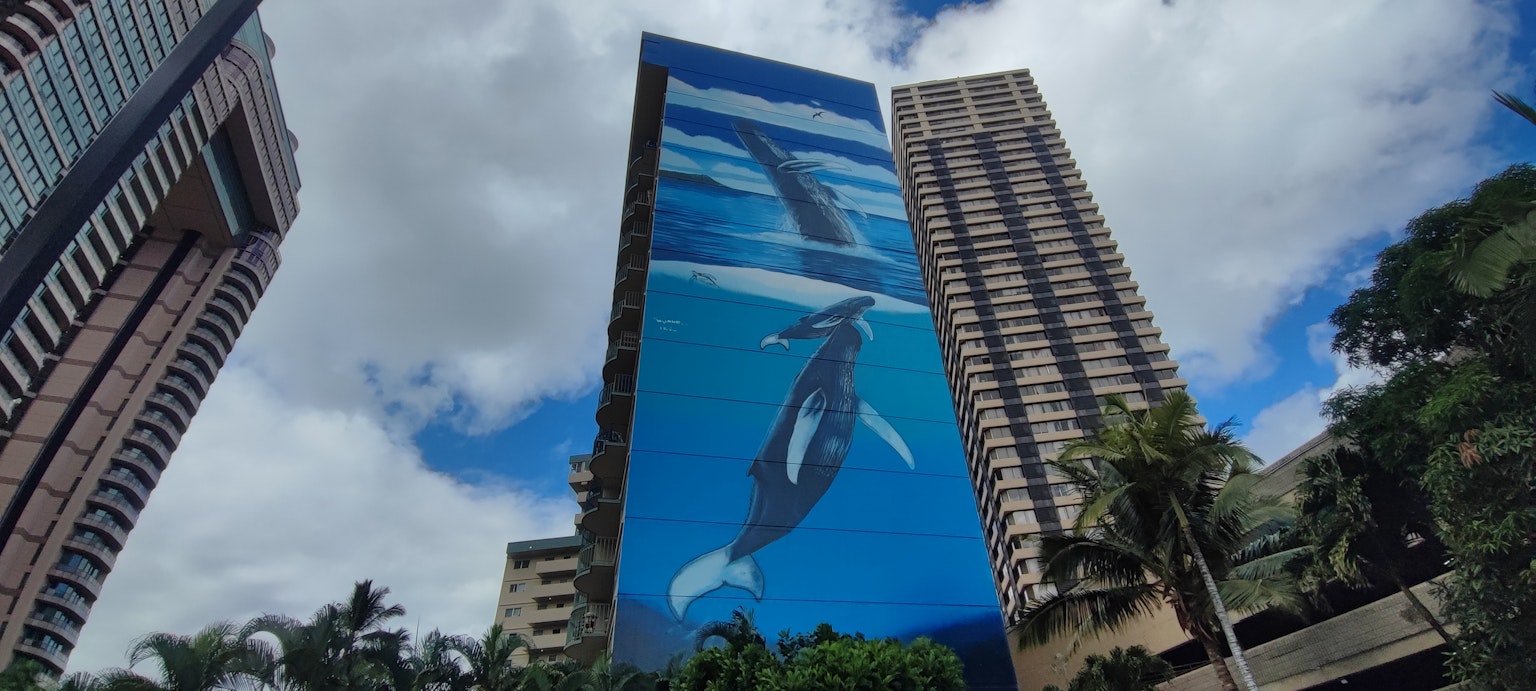 Mural ikan paus di gedung tinggi di bawah langit biru