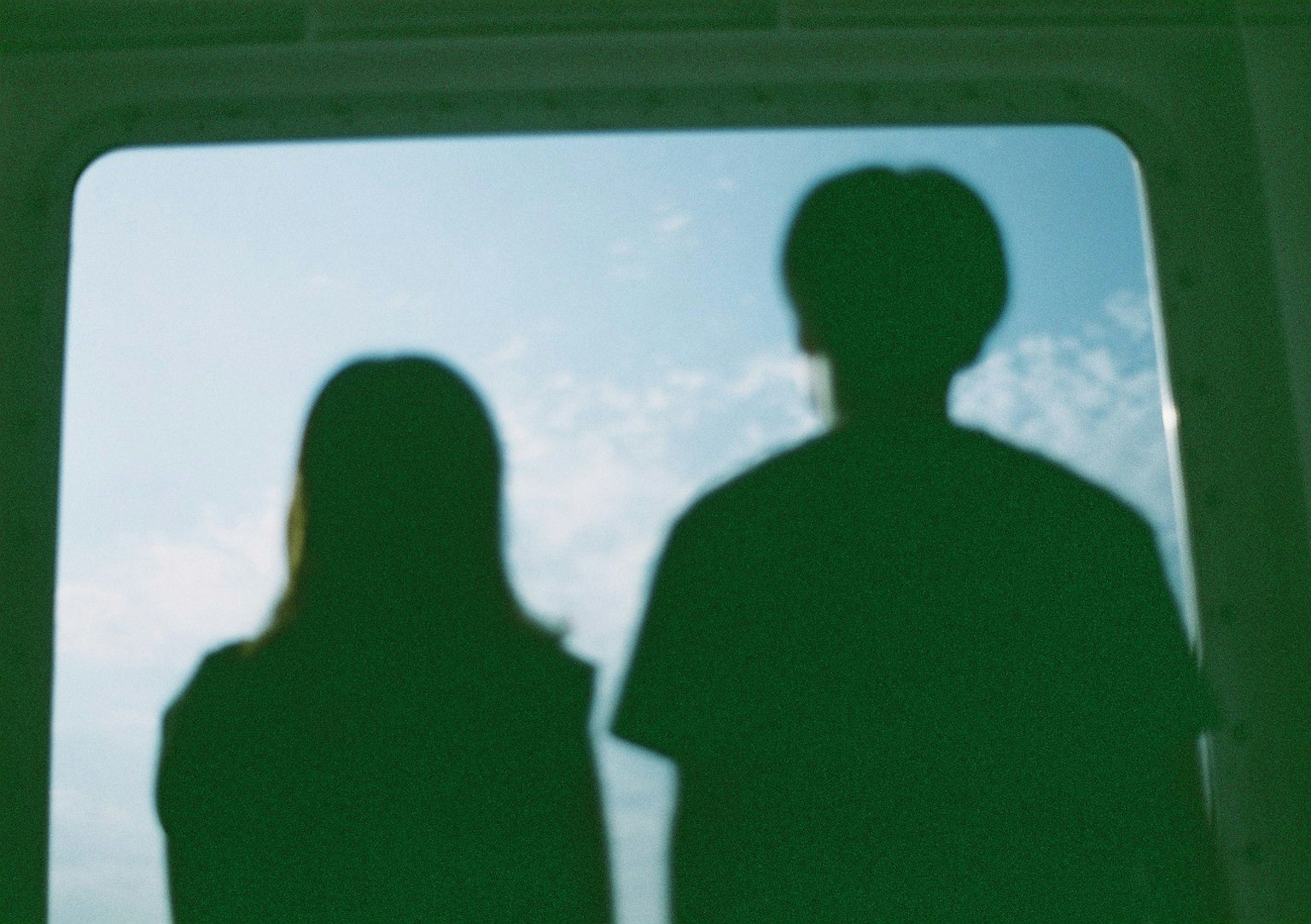Silhouette di due persone viste attraverso una finestra Cielo blu e nuvole sullo sfondo