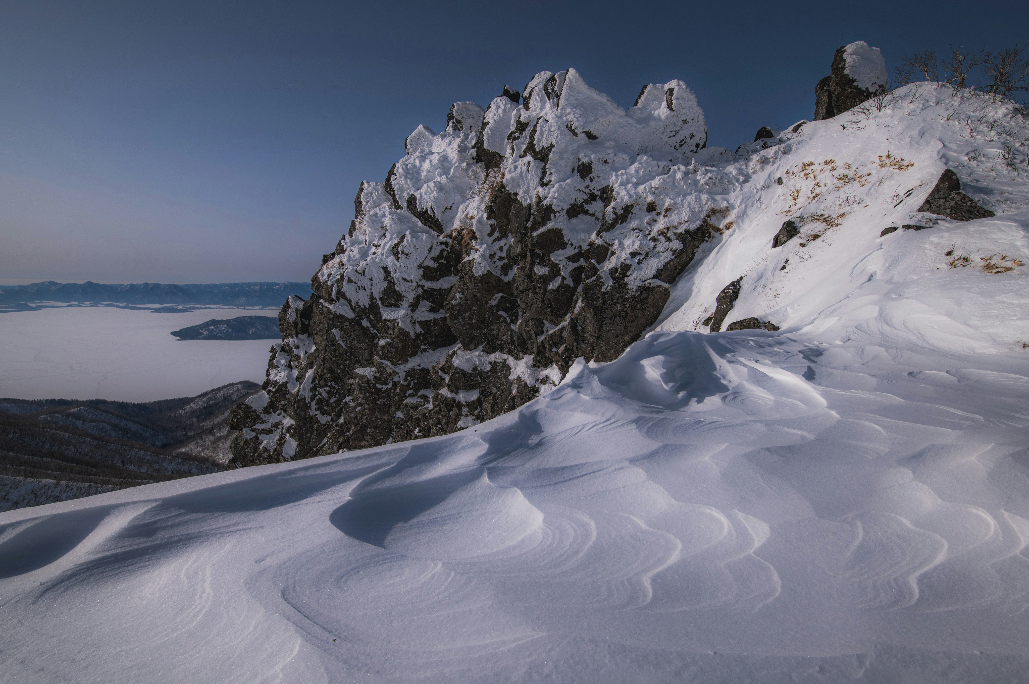 雪の斜面と岩山が広がる冬の山岳風景