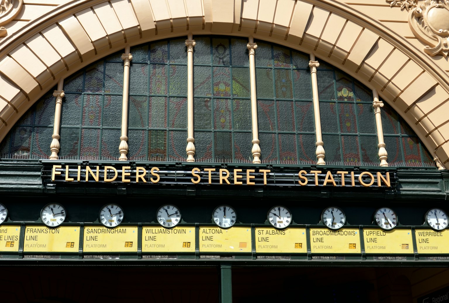 Papan nama Stasiun Flinders Street dengan desain melengkung dan beberapa jam