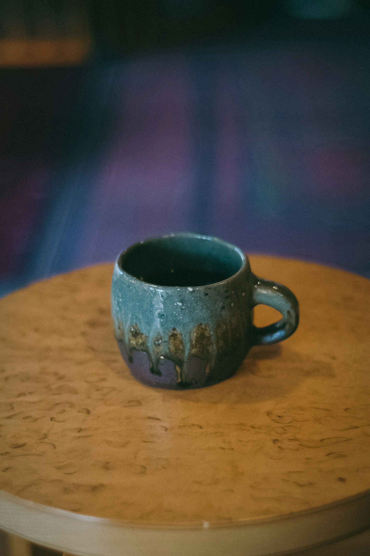 Ceramic mug in teal color placed on a wooden table
