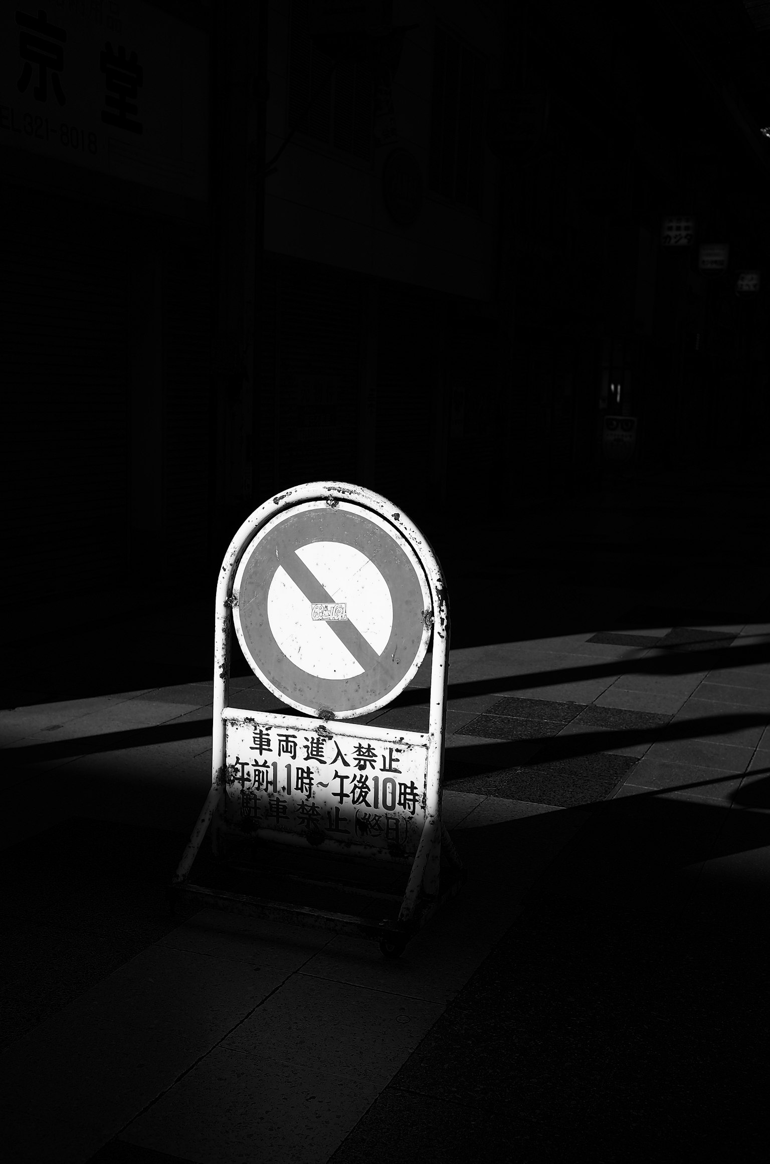 Monochrome image of a no parking sign in a city at night