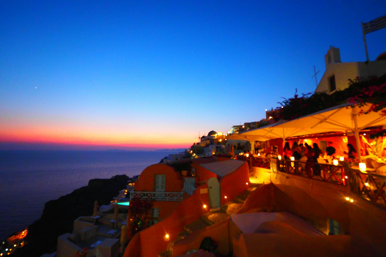 Coucher de soleil à Santorin avec terrasse illuminée et vue sur l'océan