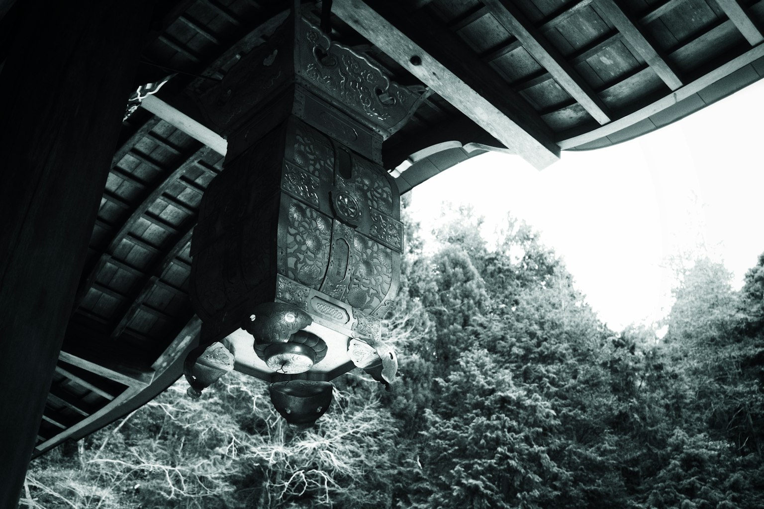 나무 지붕 아래에 있는 사원 종의 흑백 이미지