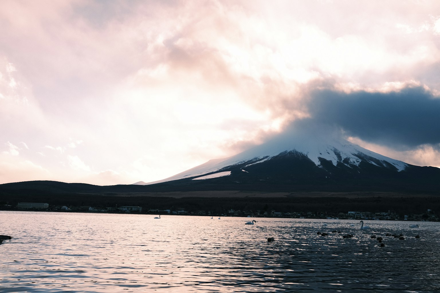 Pemandangan indah Gunung Fuji dengan danau di latar depan dan awan menutupi puncak