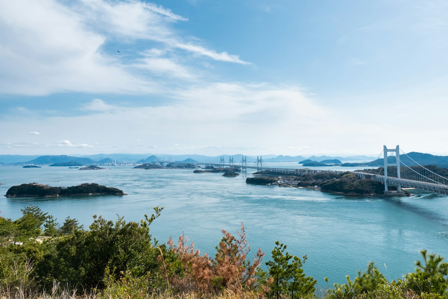 Pemandangan laut biru dengan jembatan di kejauhan