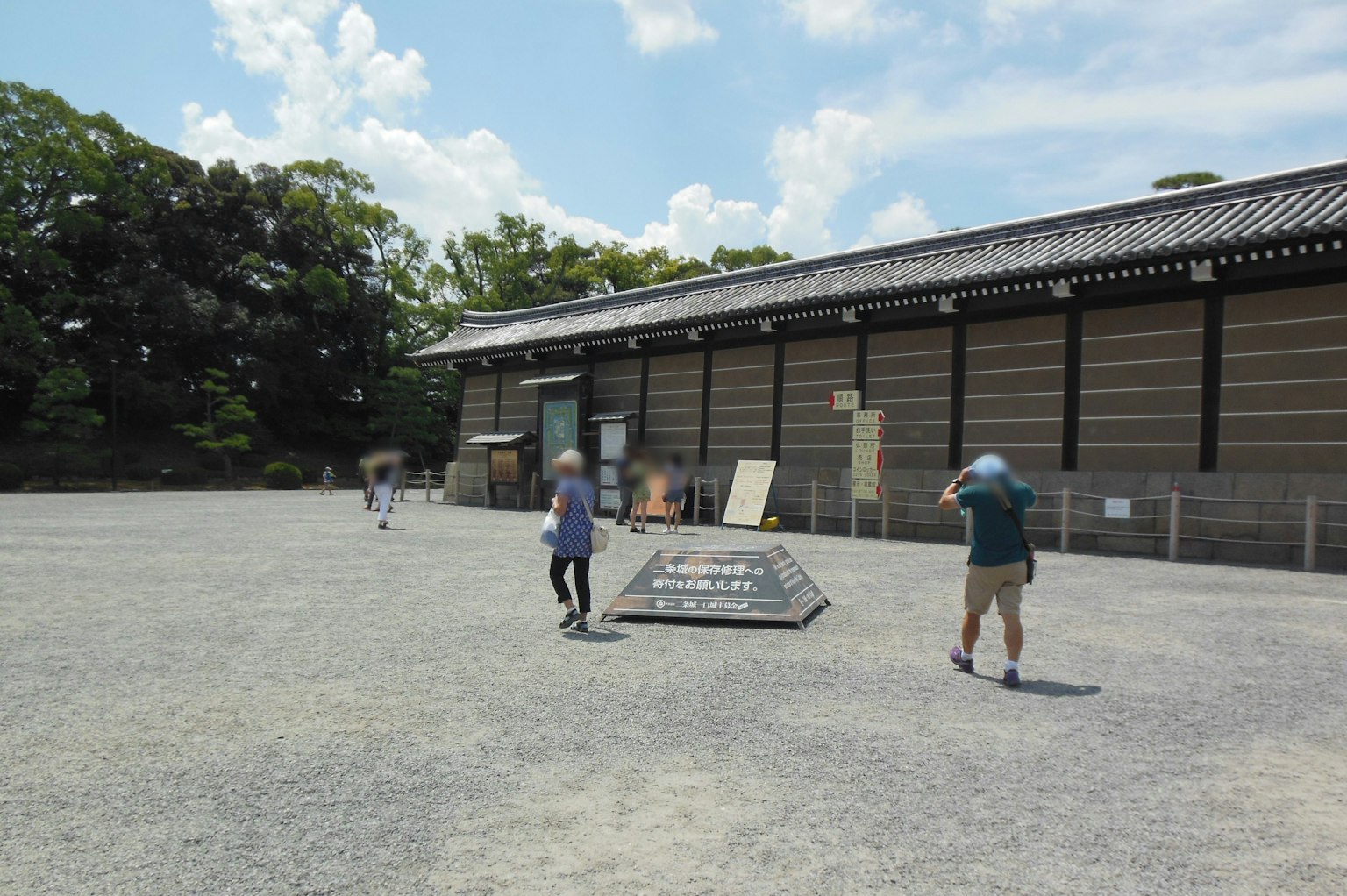People walking in a spacious area in front of a historical building under a blue sky