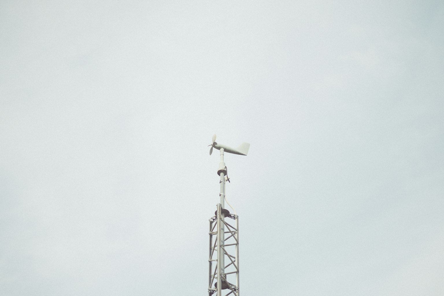 Torre di comunicazione con una banderuola sotto un cielo pallido