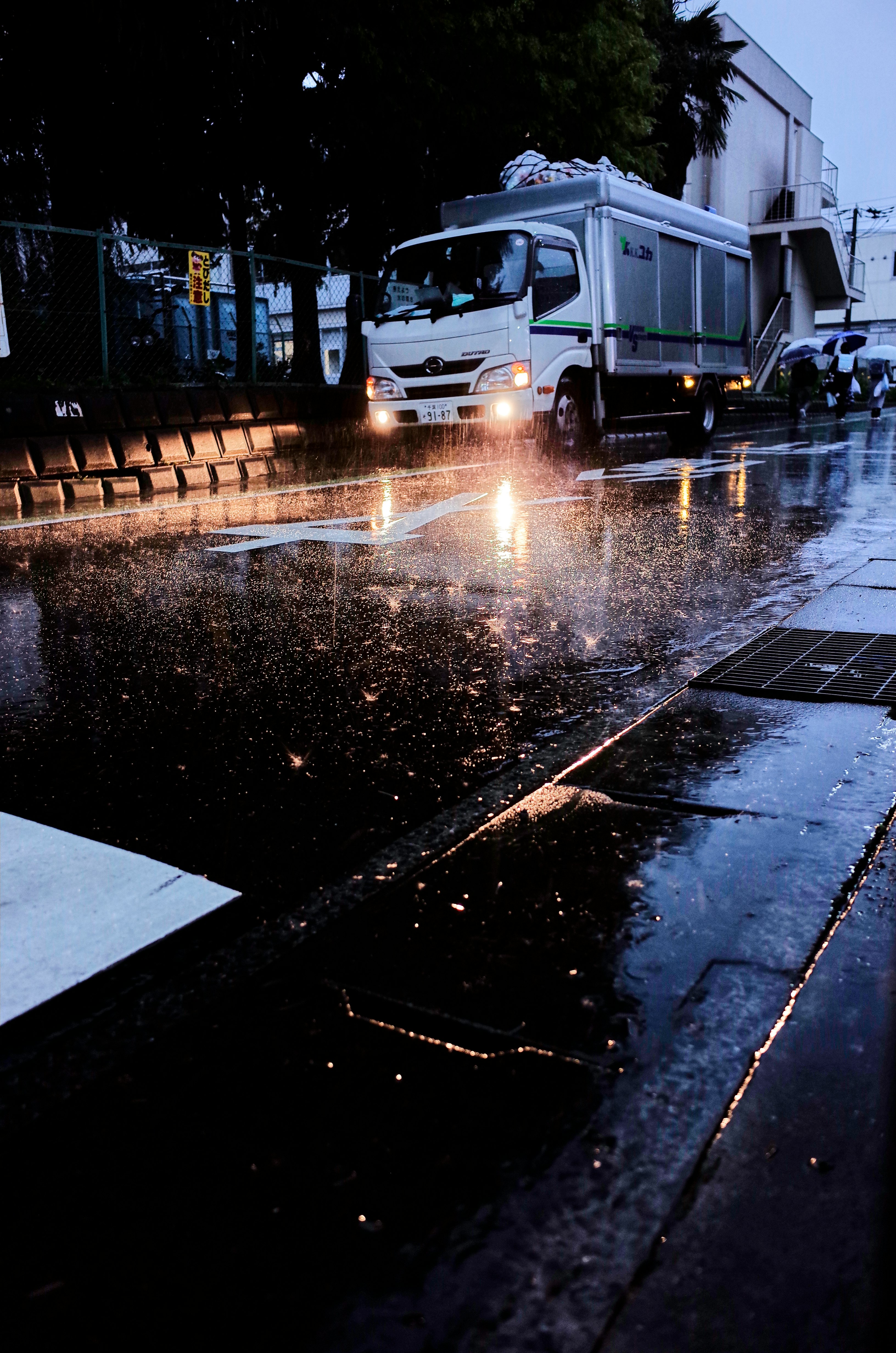 雨の夜に走るトラックのヘッドライトと濡れた道路