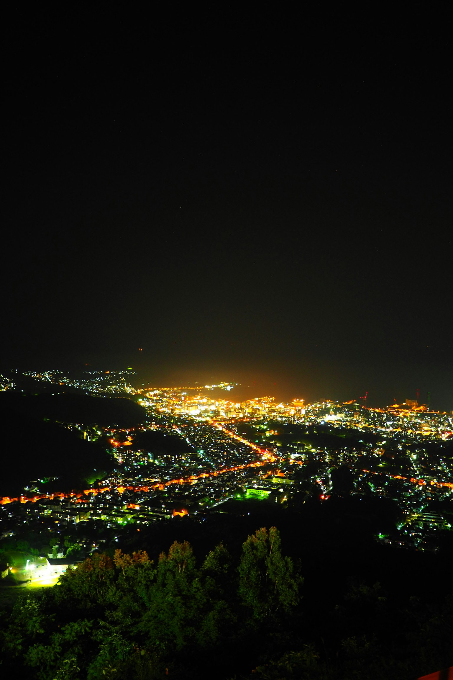 Vue nocturne d'une ville illuminée depuis une montagne