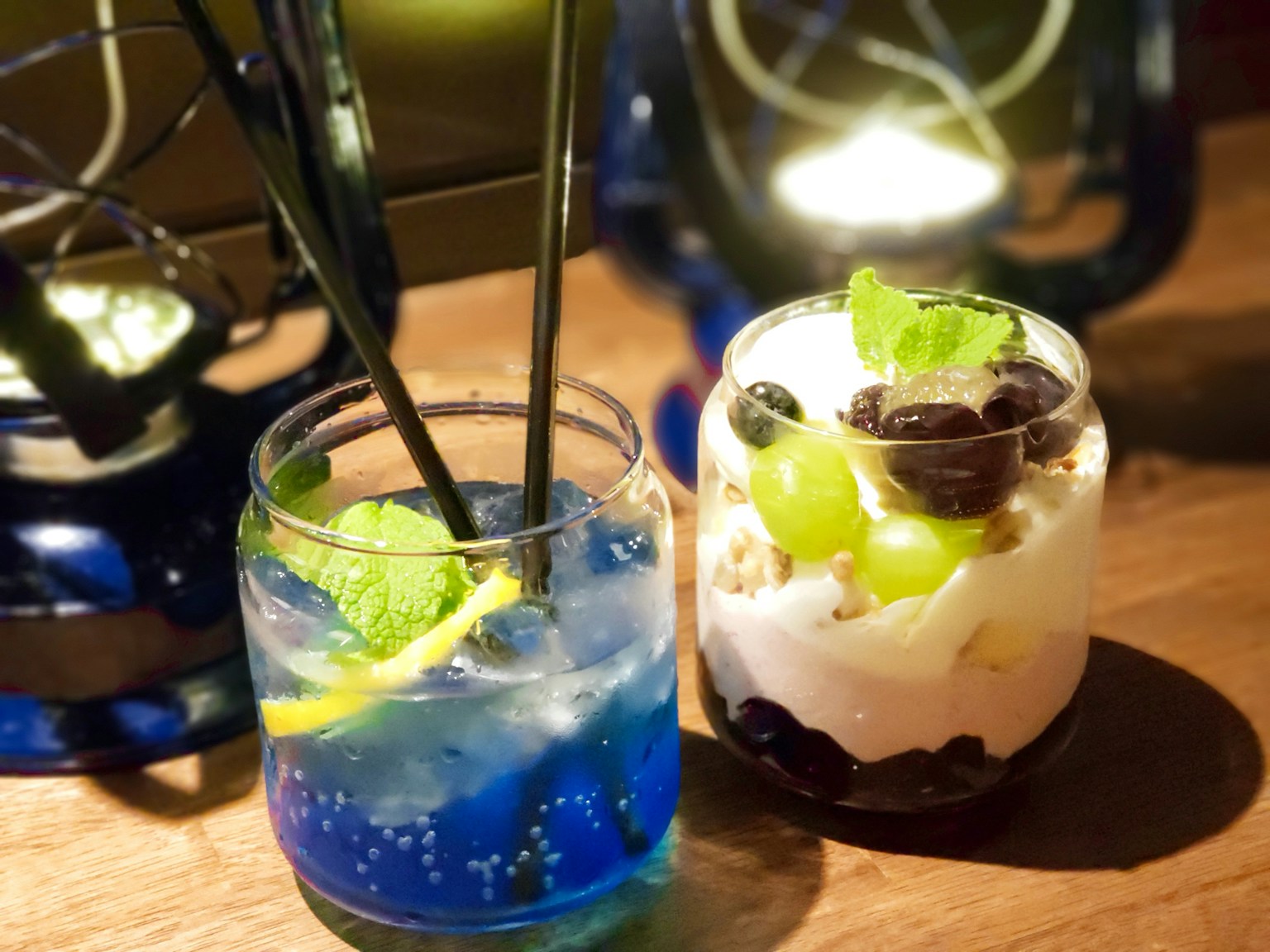 青いカクテルとデザートカップの画像、木のテーブルの上