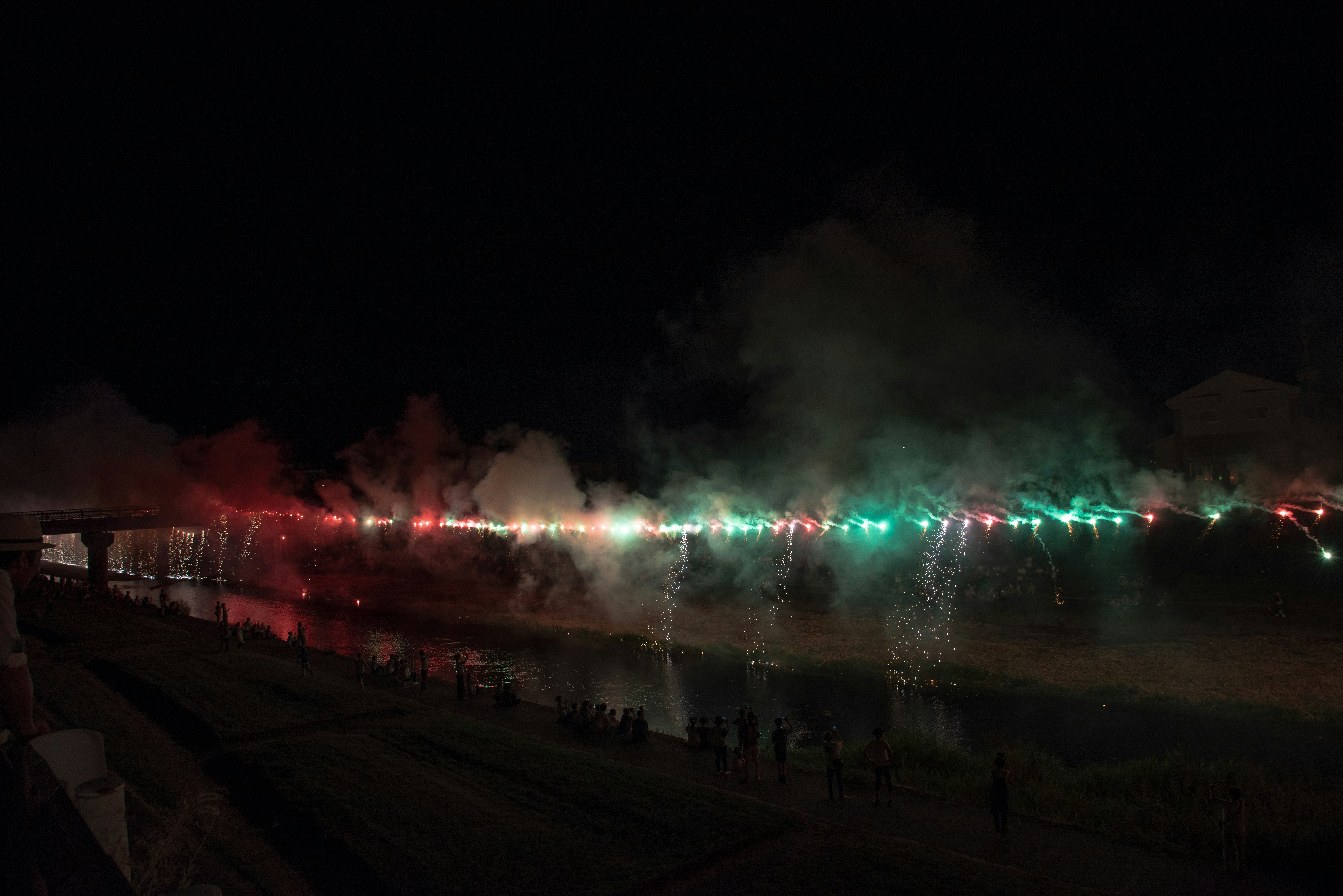 夜の川沿いに並ぶイルミネーションの光