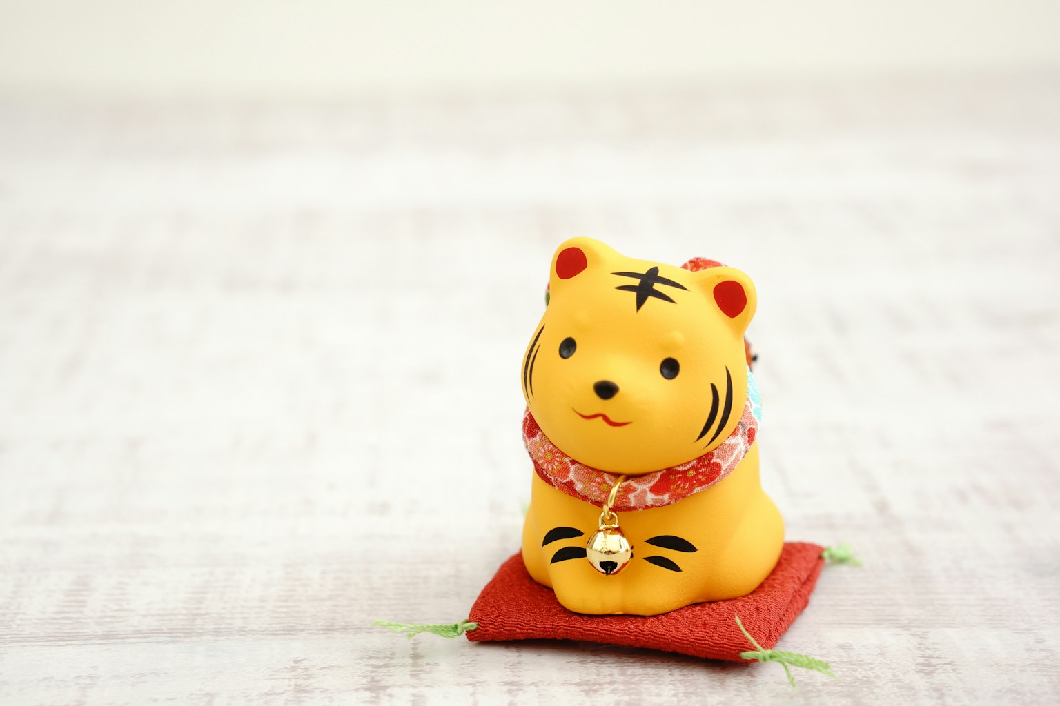 A cute tiger figurine sitting on a red cushion