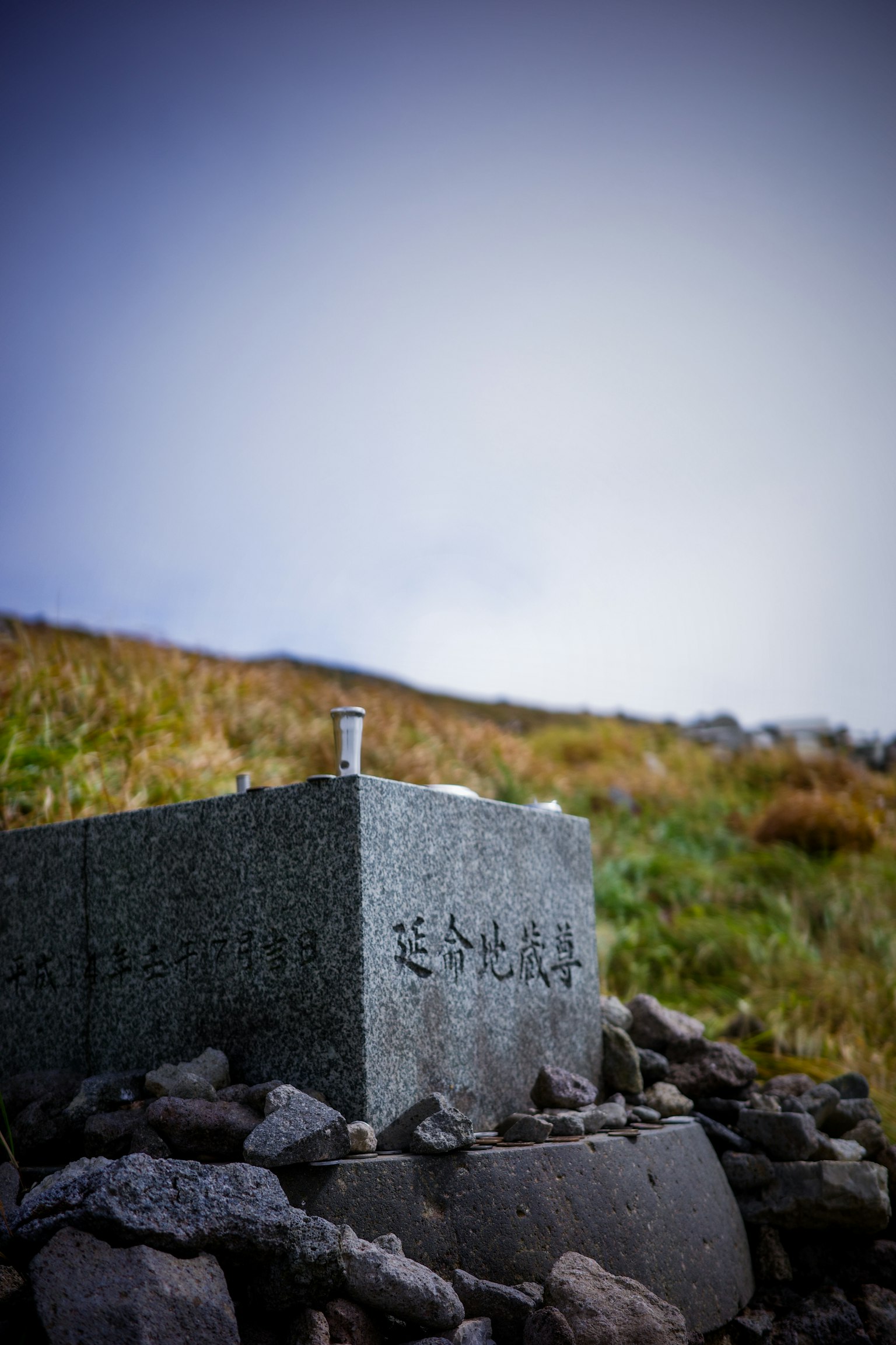 돌로 둘러싸인 기념비가 풀밭に立っている風景