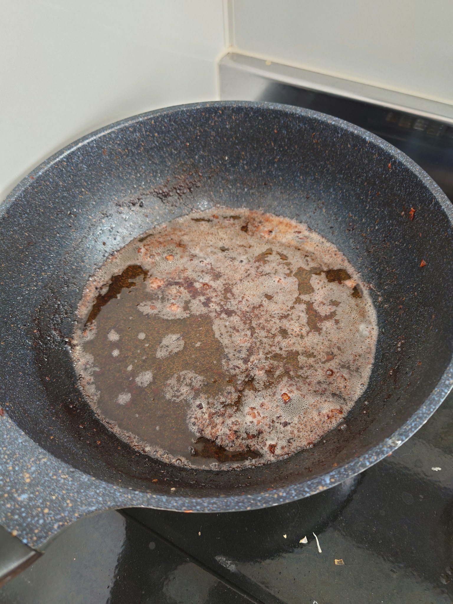 Padella sporca con olio e residui di cibo