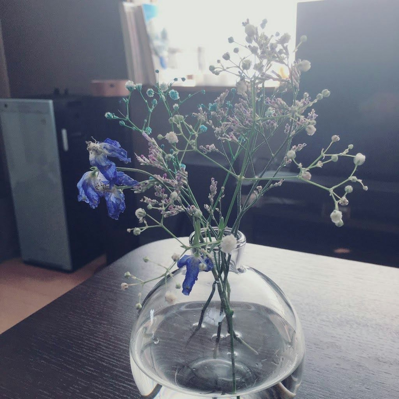 การจัดดอกไม้สีน้ำเงินและดอกไม้สีขาวเล็กๆ ในแจกันใส