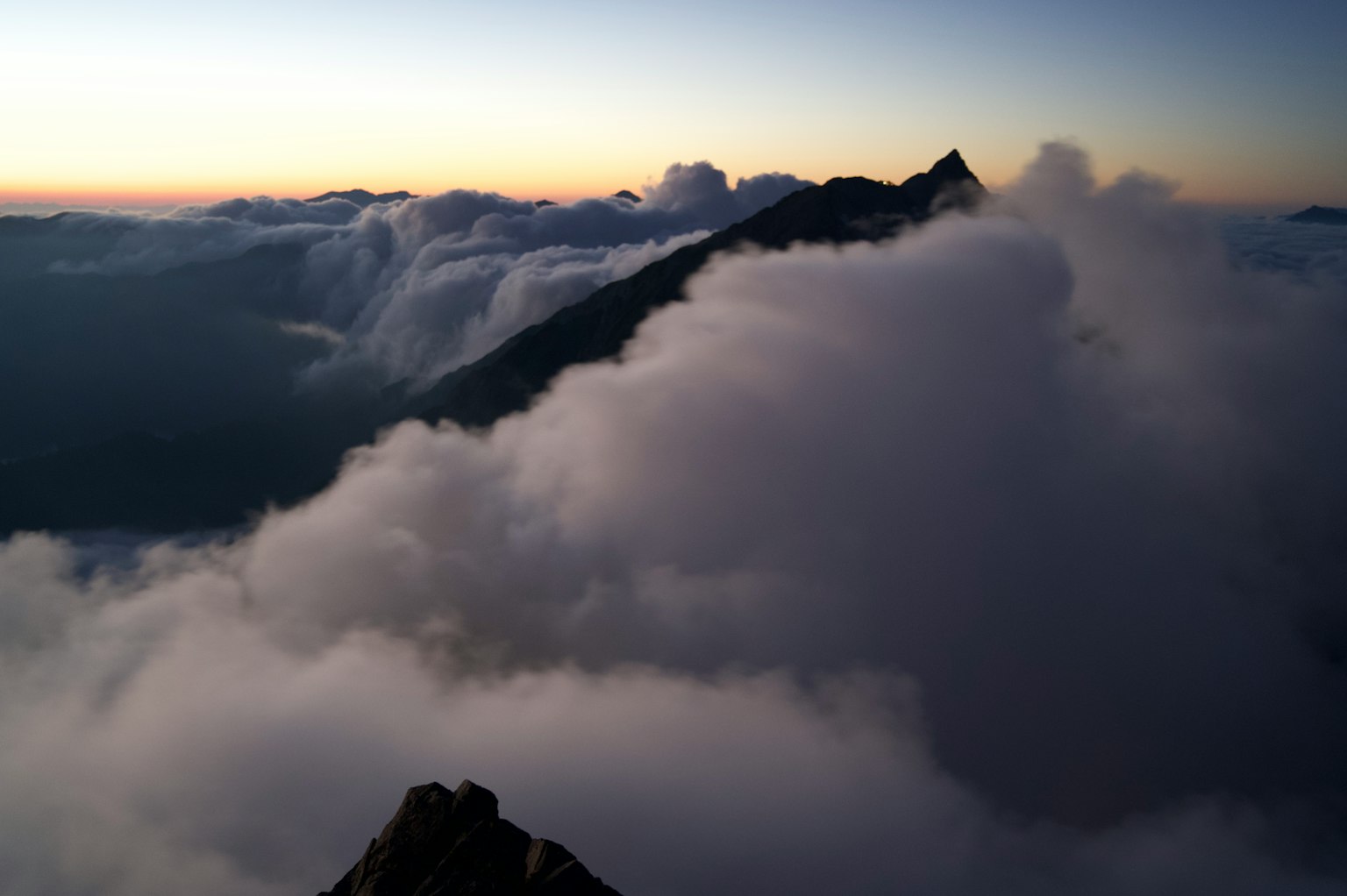 Paisaje montañoso cubierto de nubes con un cielo al atardecer