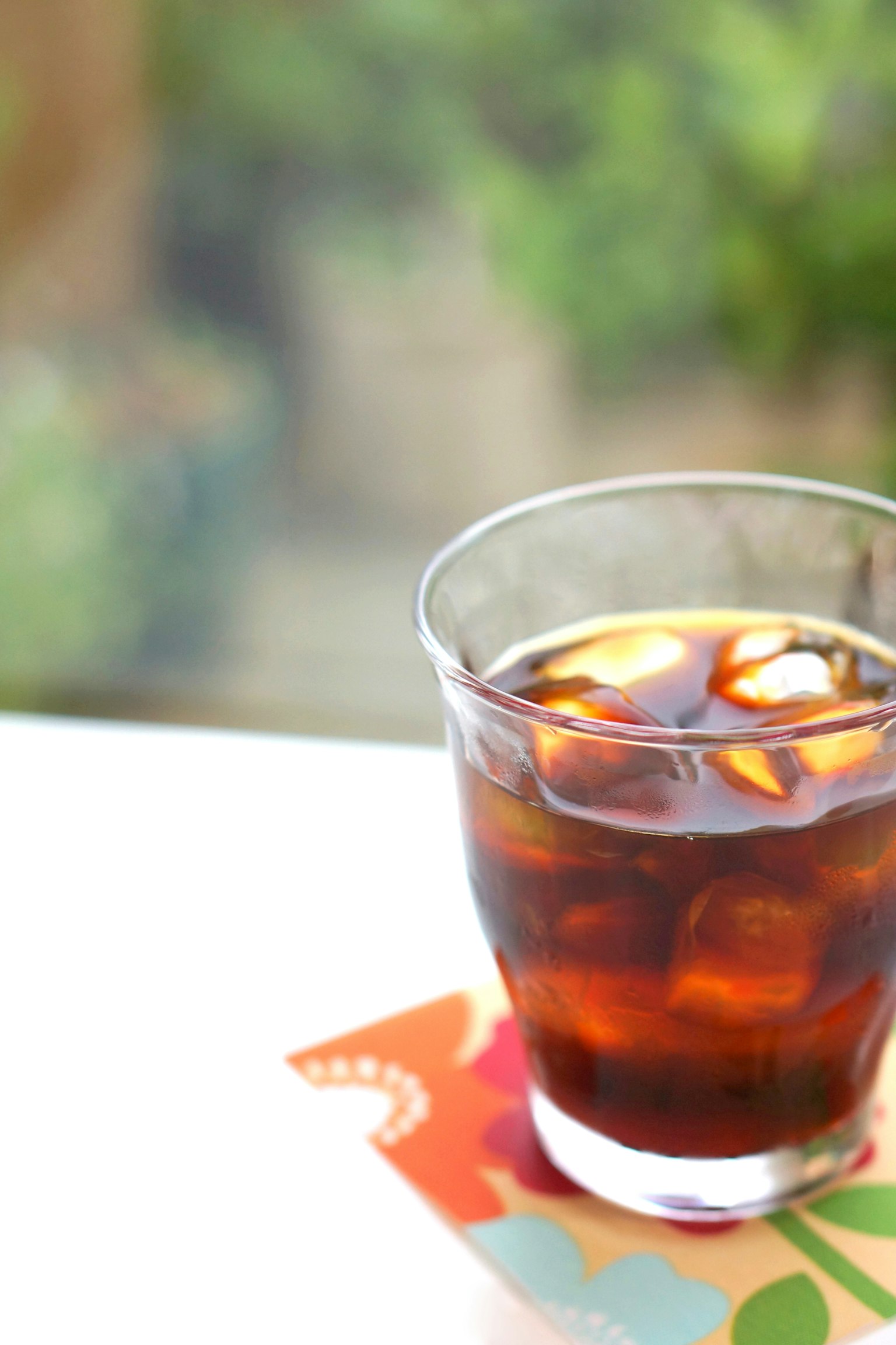 Segelas kopi es dengan es batu di atas tatakan warna-warni