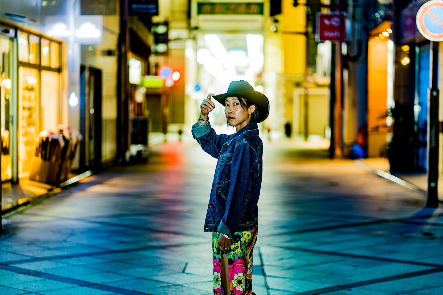 Un ragazzo con un cappello da cowboy in piedi in una strada notturna