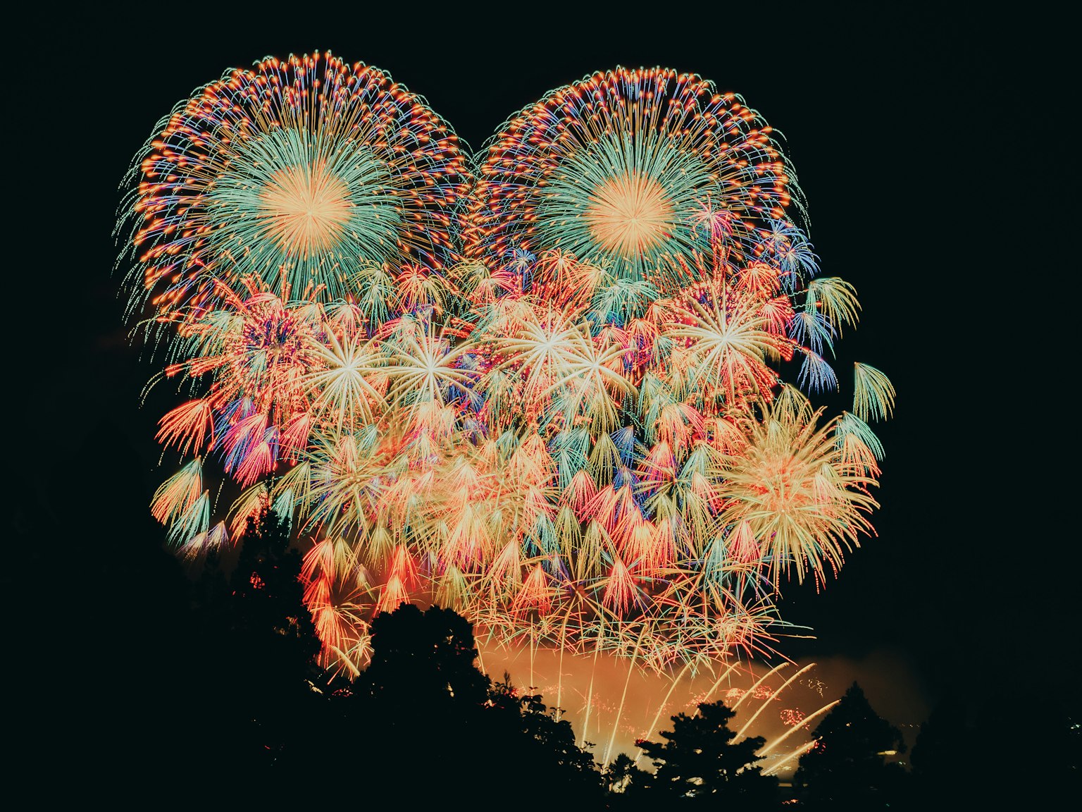 Spectacle de feux d'artifice colorés dans le ciel nocturne formant une forme de cœur