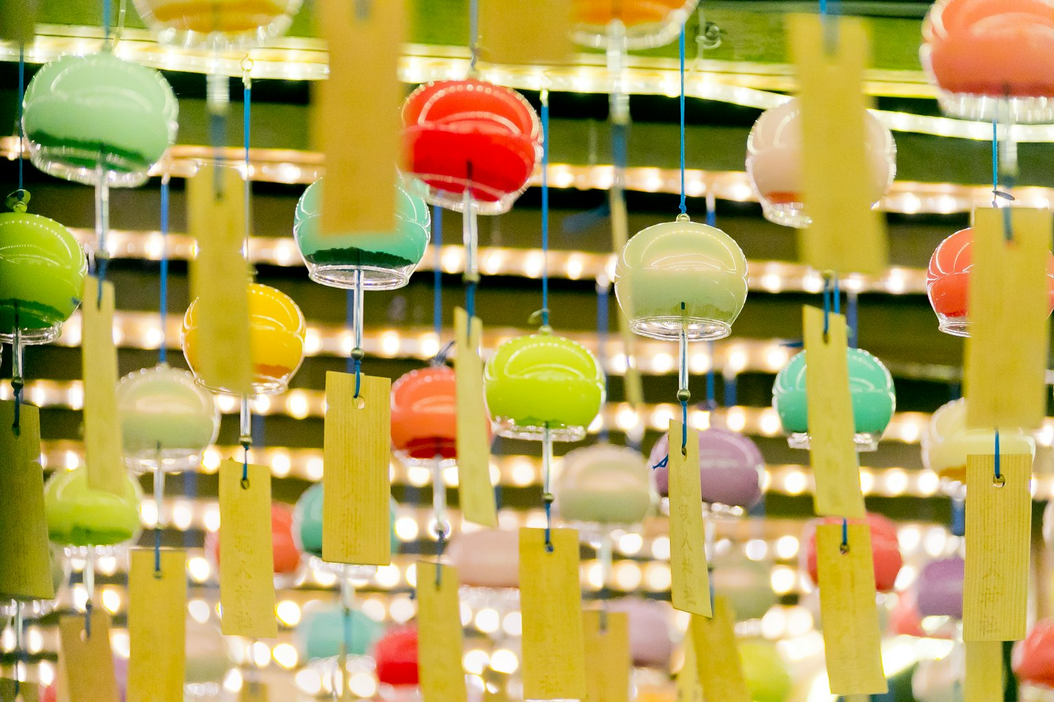 Bunte Windspiele und gelbe Tanzaku hängen in einer lebhaften Ausstellung