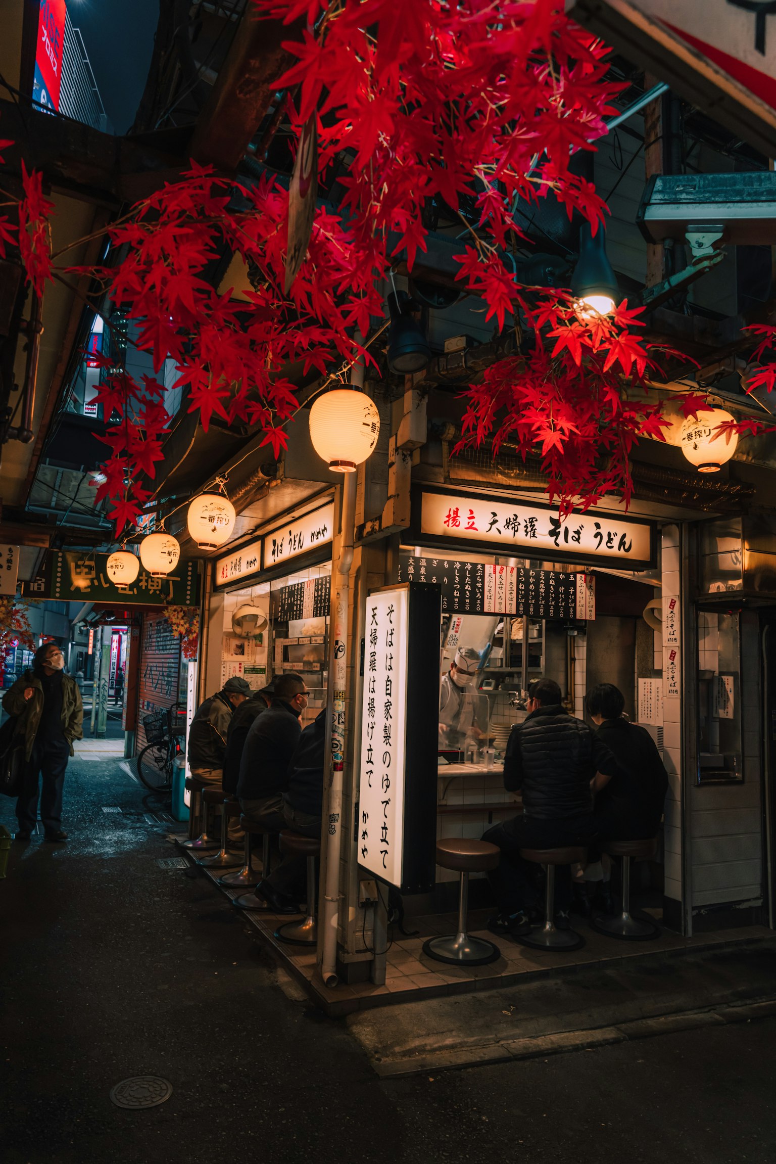 夜晚的居酒屋场景，红色枫叶和灯笼