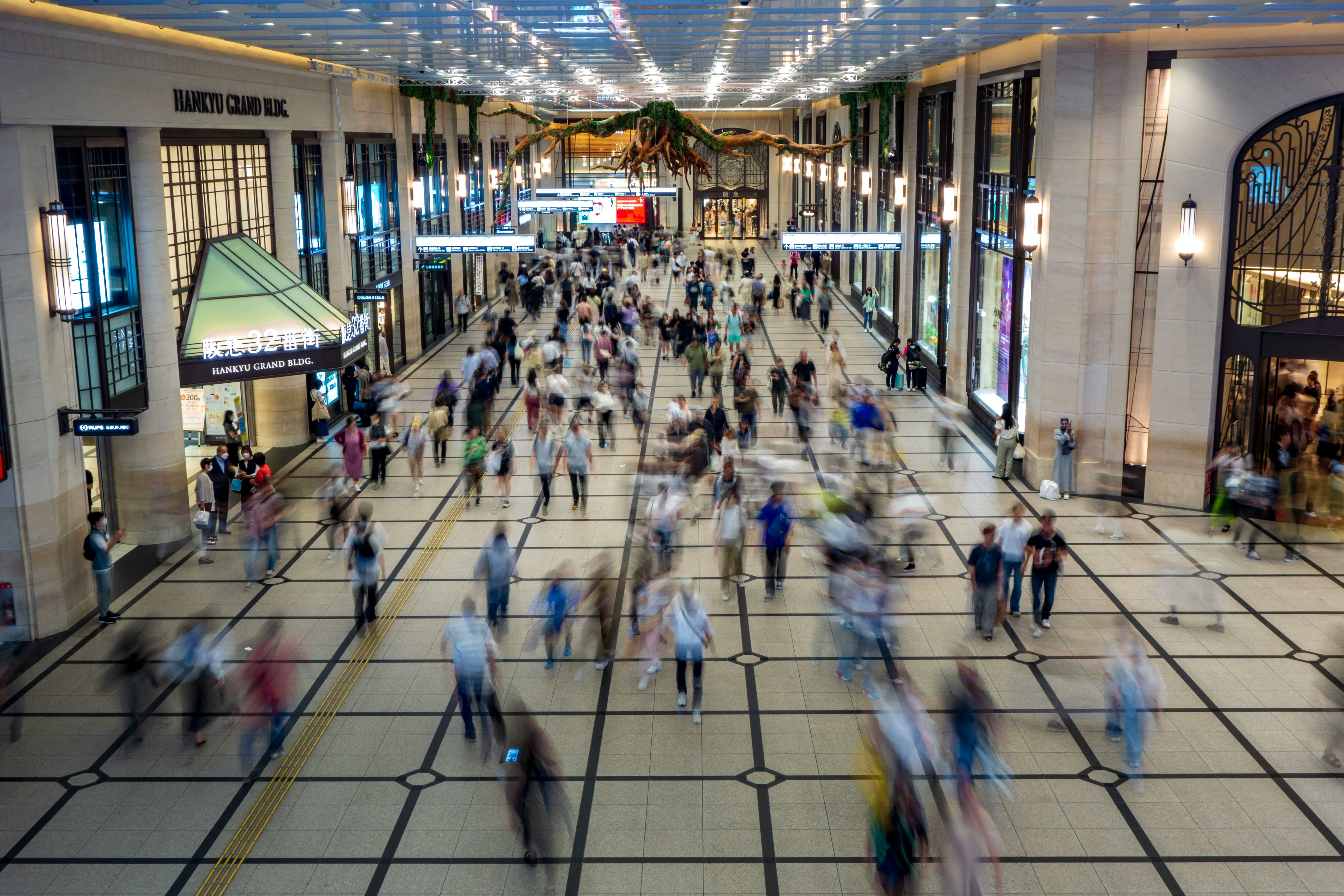 アーケード状の屋内通路に人が行き交う駅構内の風景