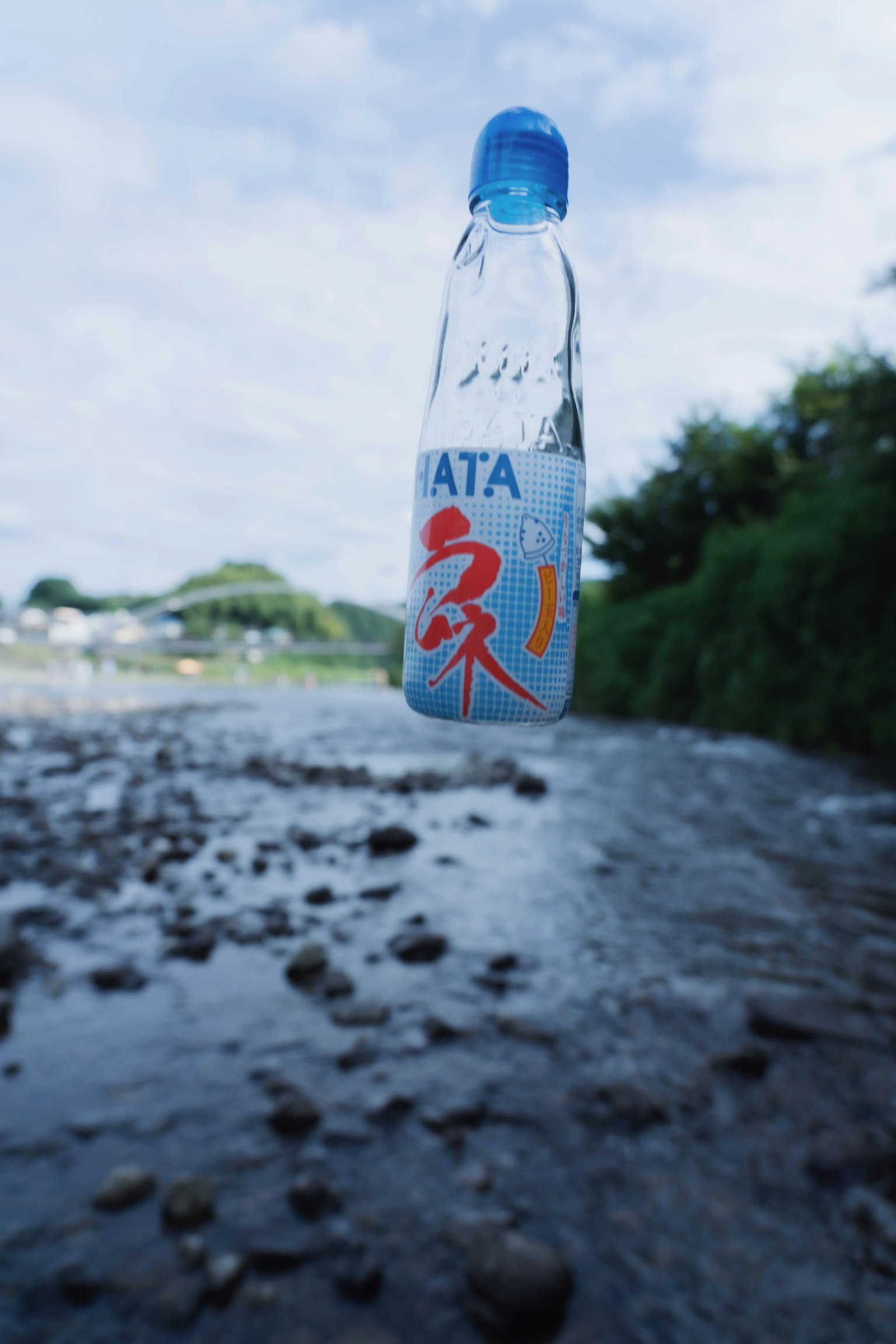 透明塑料瓶漂浮在河流上，配有蓝色瓶盖和红色字母