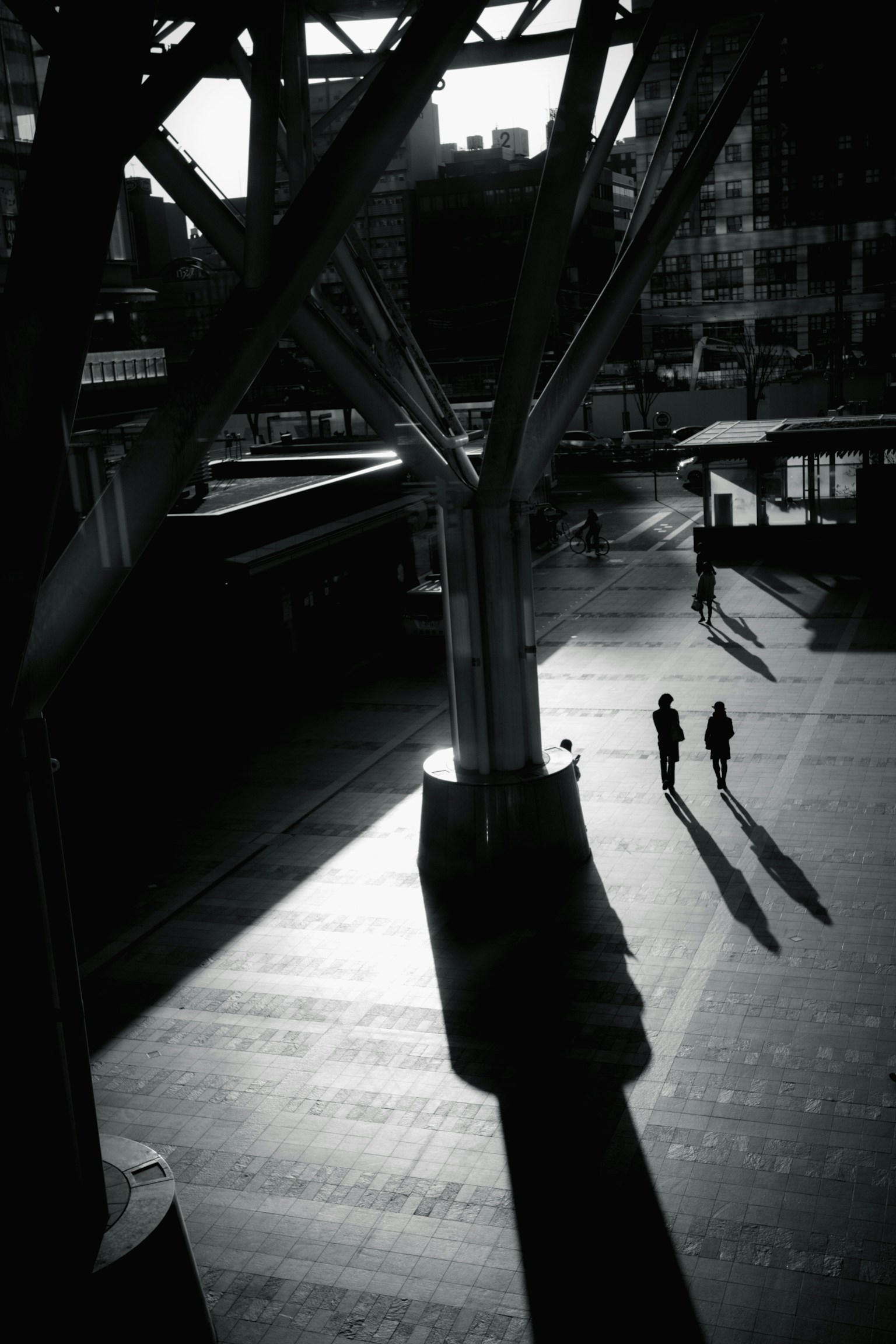 High-contrast black and white urban scene with long shadows of two people
