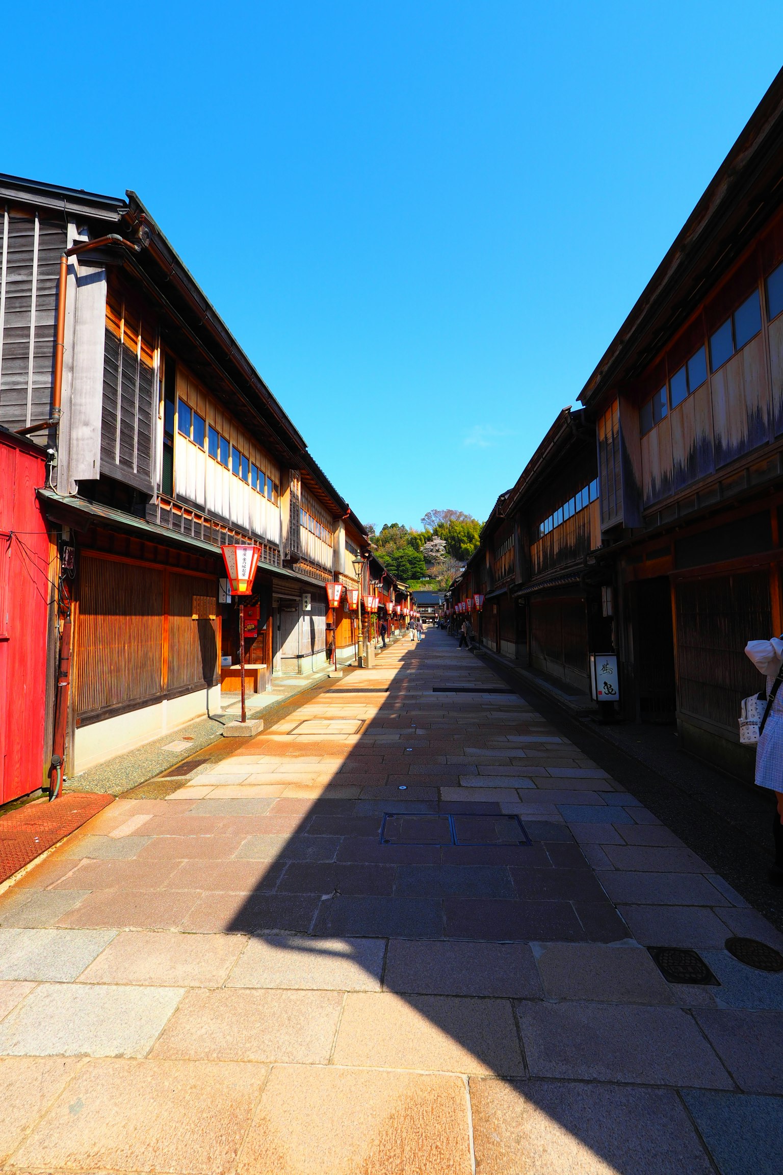 Rue étroite bordée de bâtiments en bois traditionnels japonais sous un ciel bleu clair