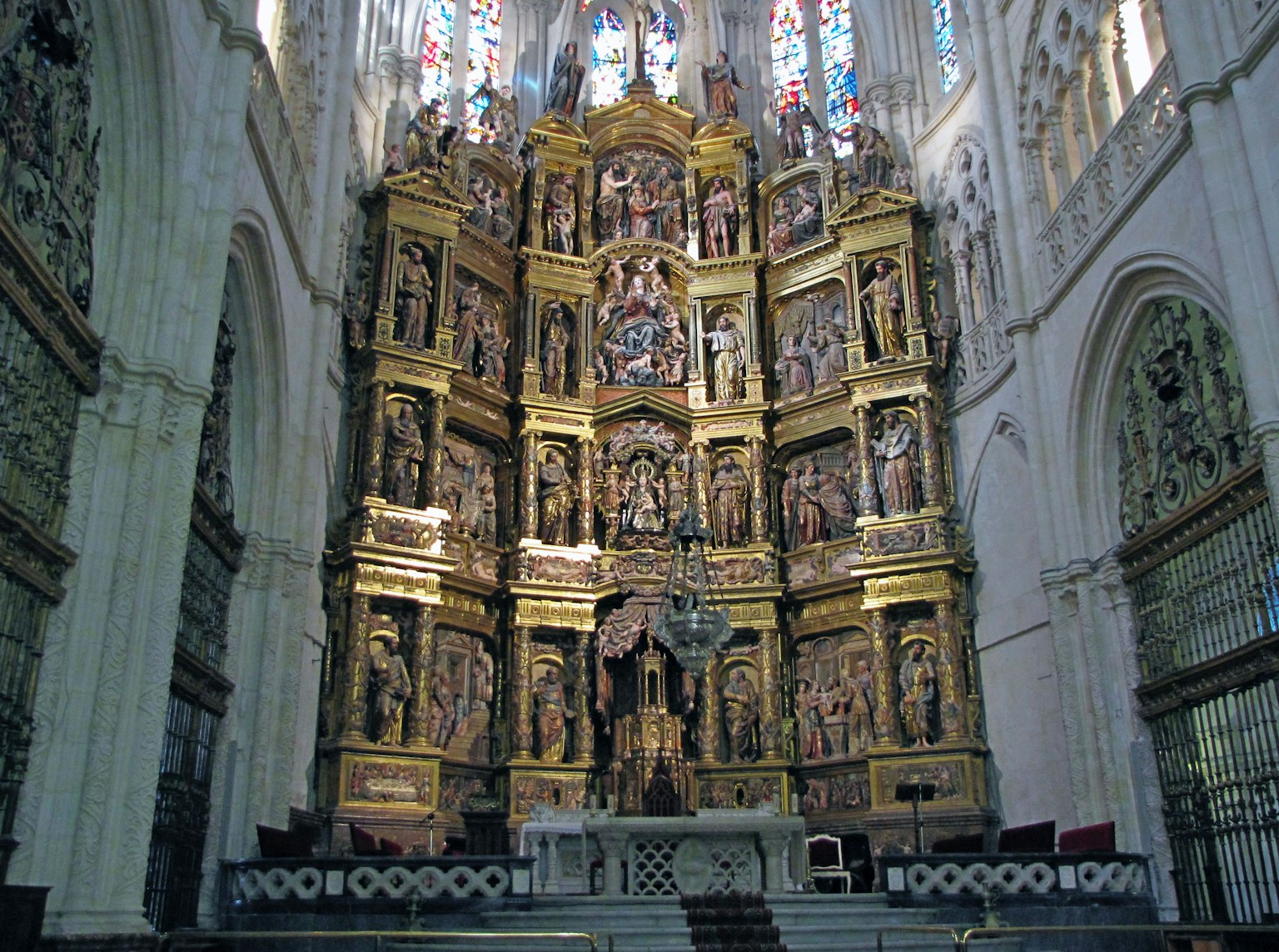 Autel d'église finement sculpté avec des décorations dorées et des vitraux colorés illuminant l'intérieur