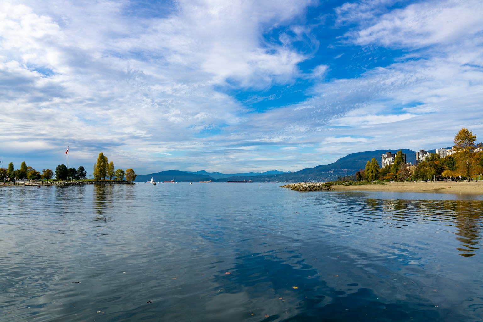 Vista serena de un lago con cielo azul y montañas reflejadas