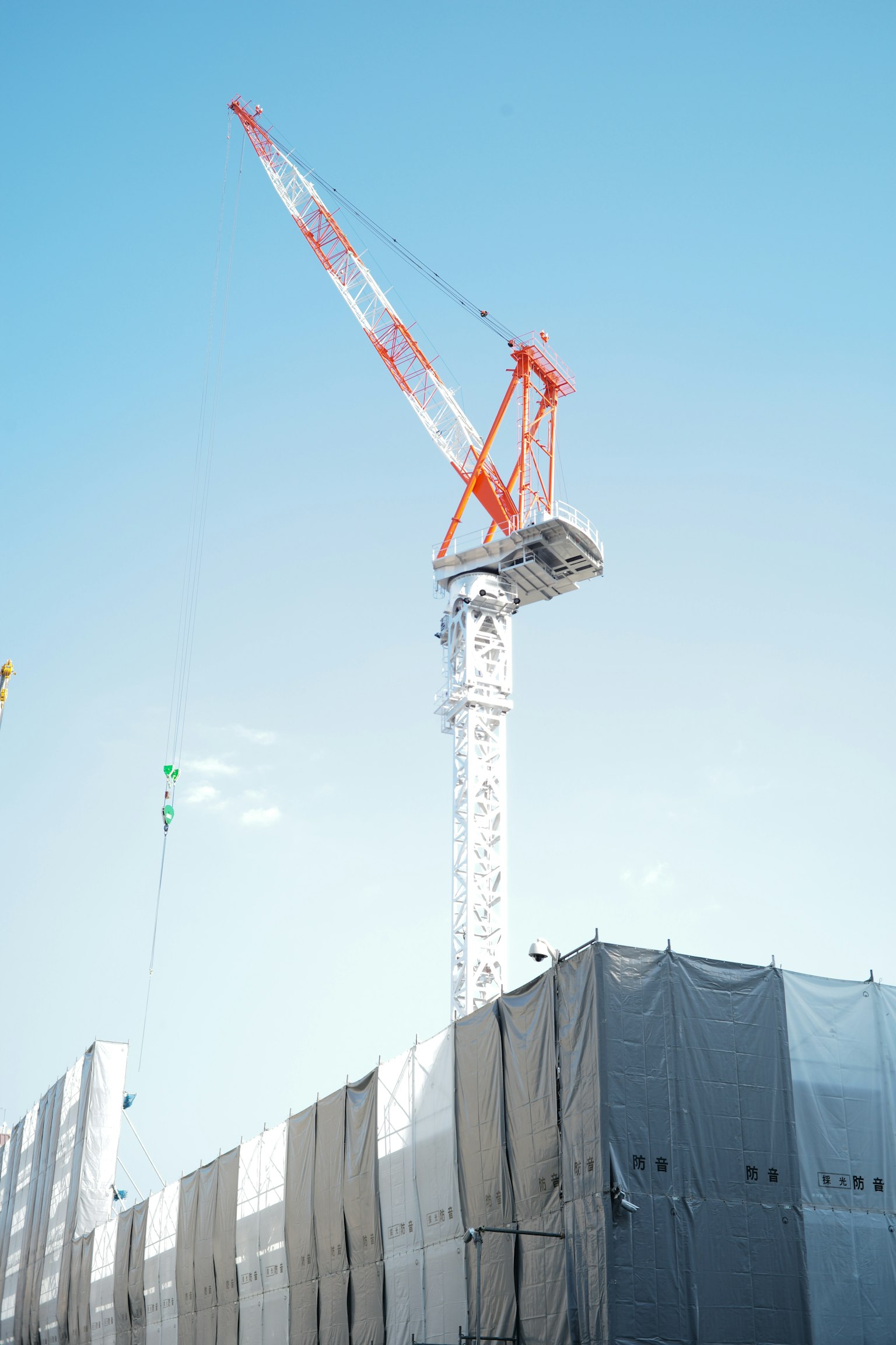 Construction crane towering over a building site under a clear blue sky