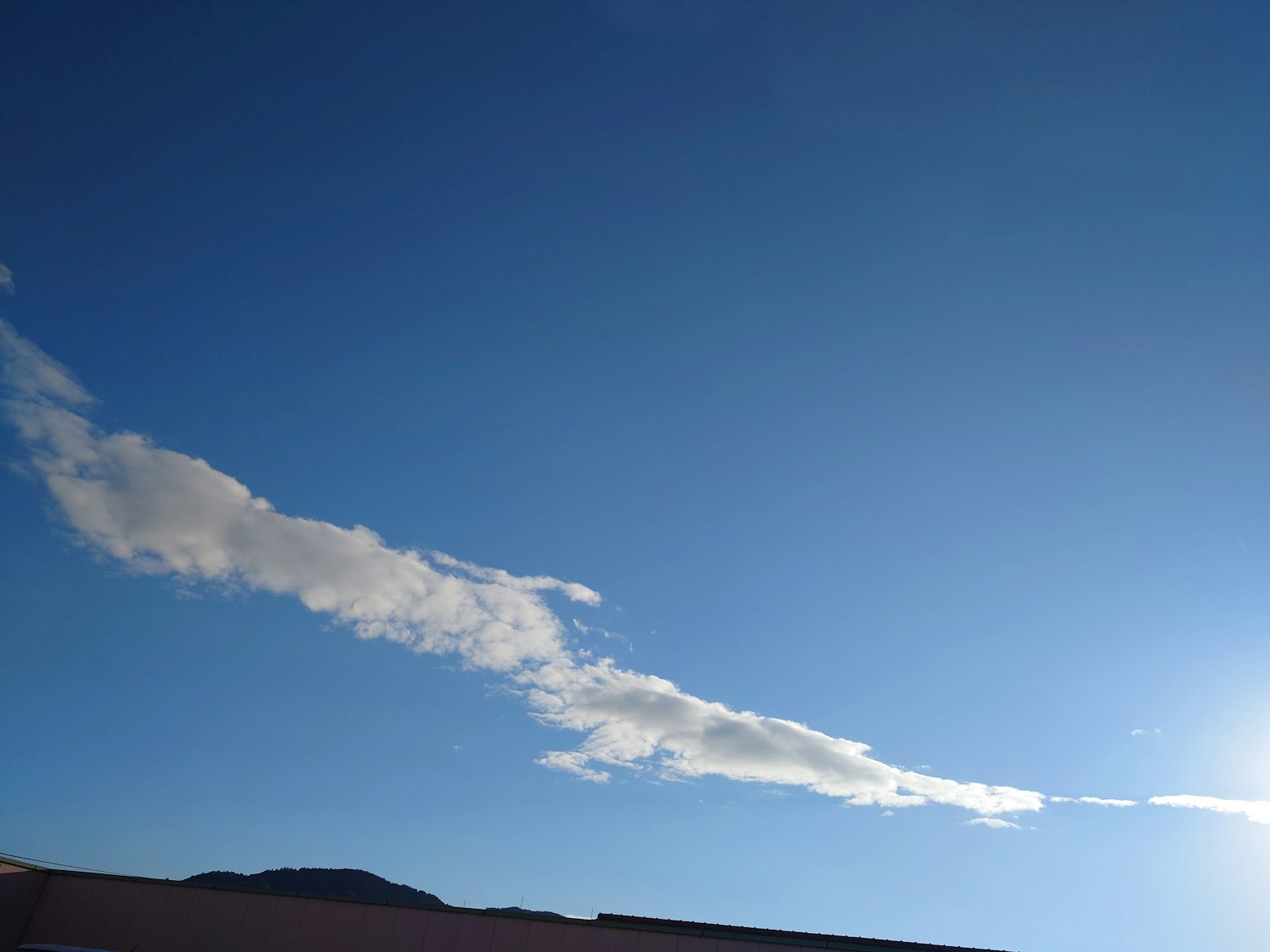 Nuvola lunga che fluttua nel cielo blu con luce solare