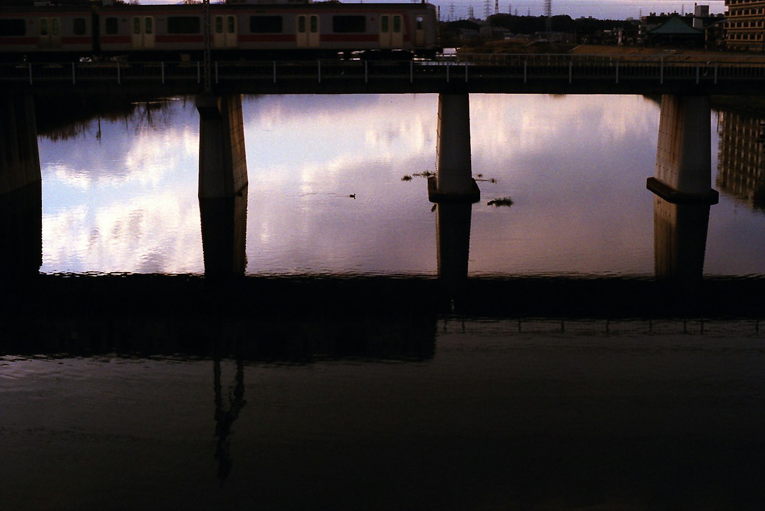 Refleksi jembatan dan warna langit di permukaan air