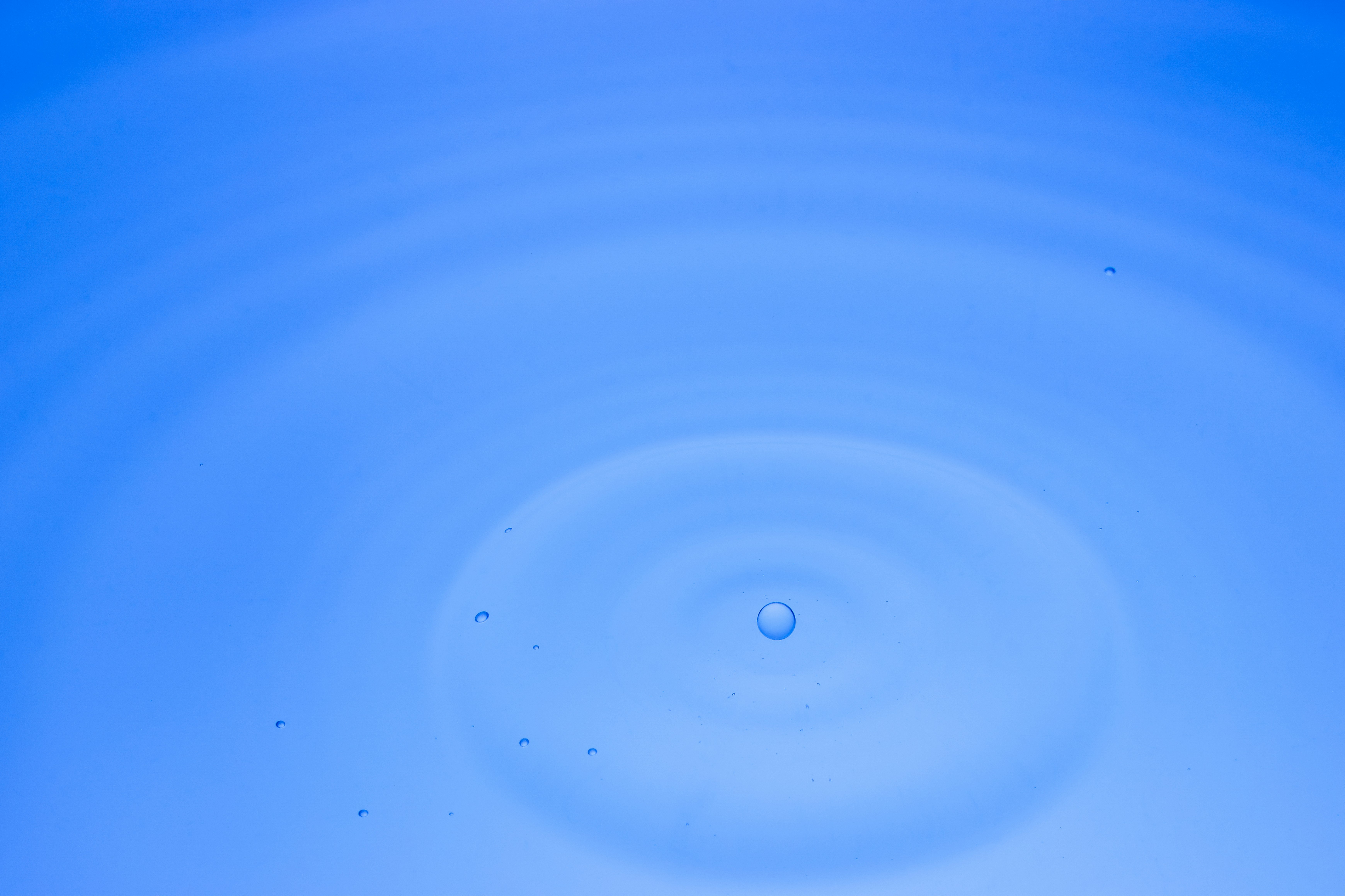 青い水面に広がる波紋と水の玉の滴