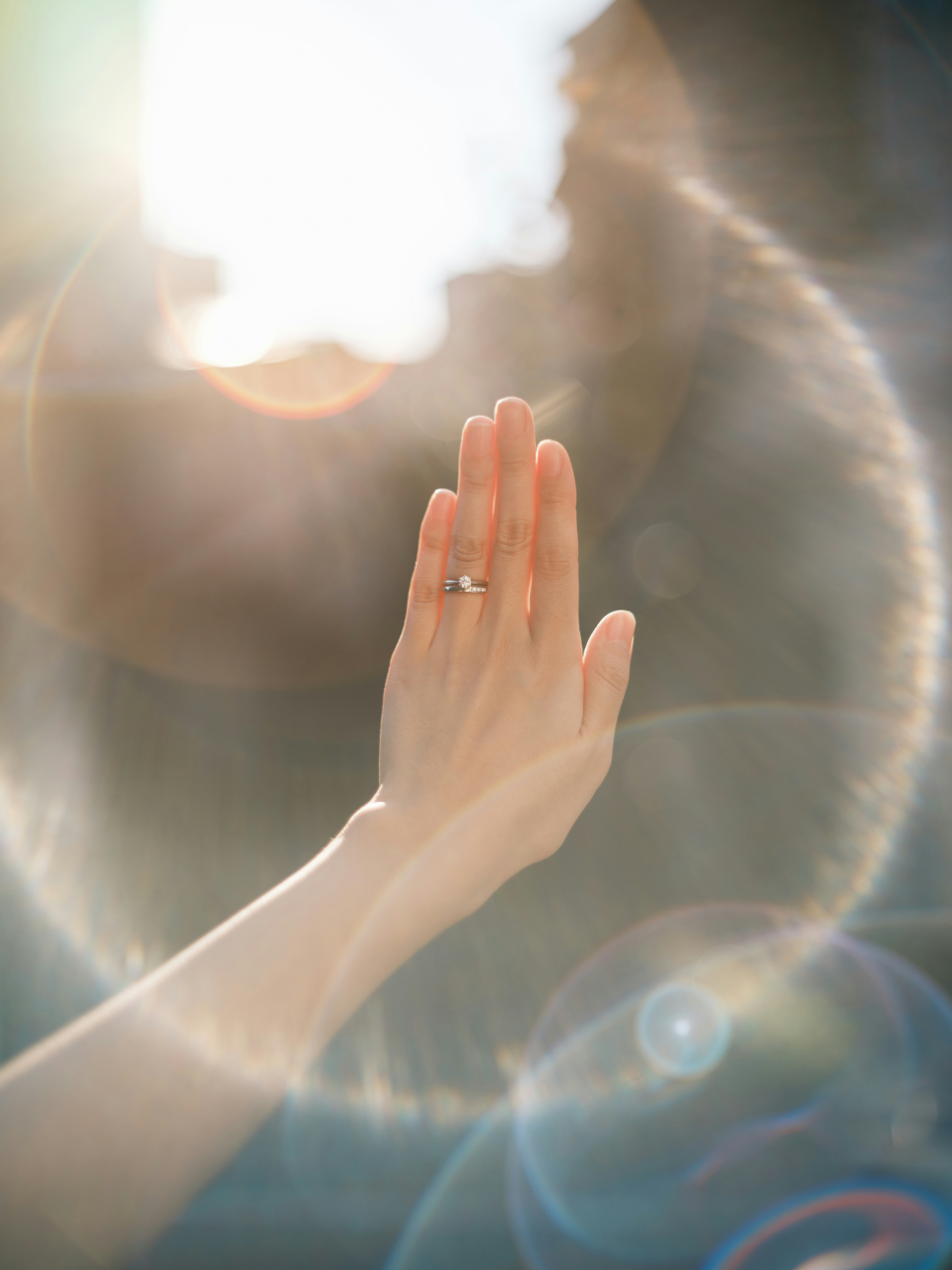 手をかざす人物のシルエットと朝日の光芒