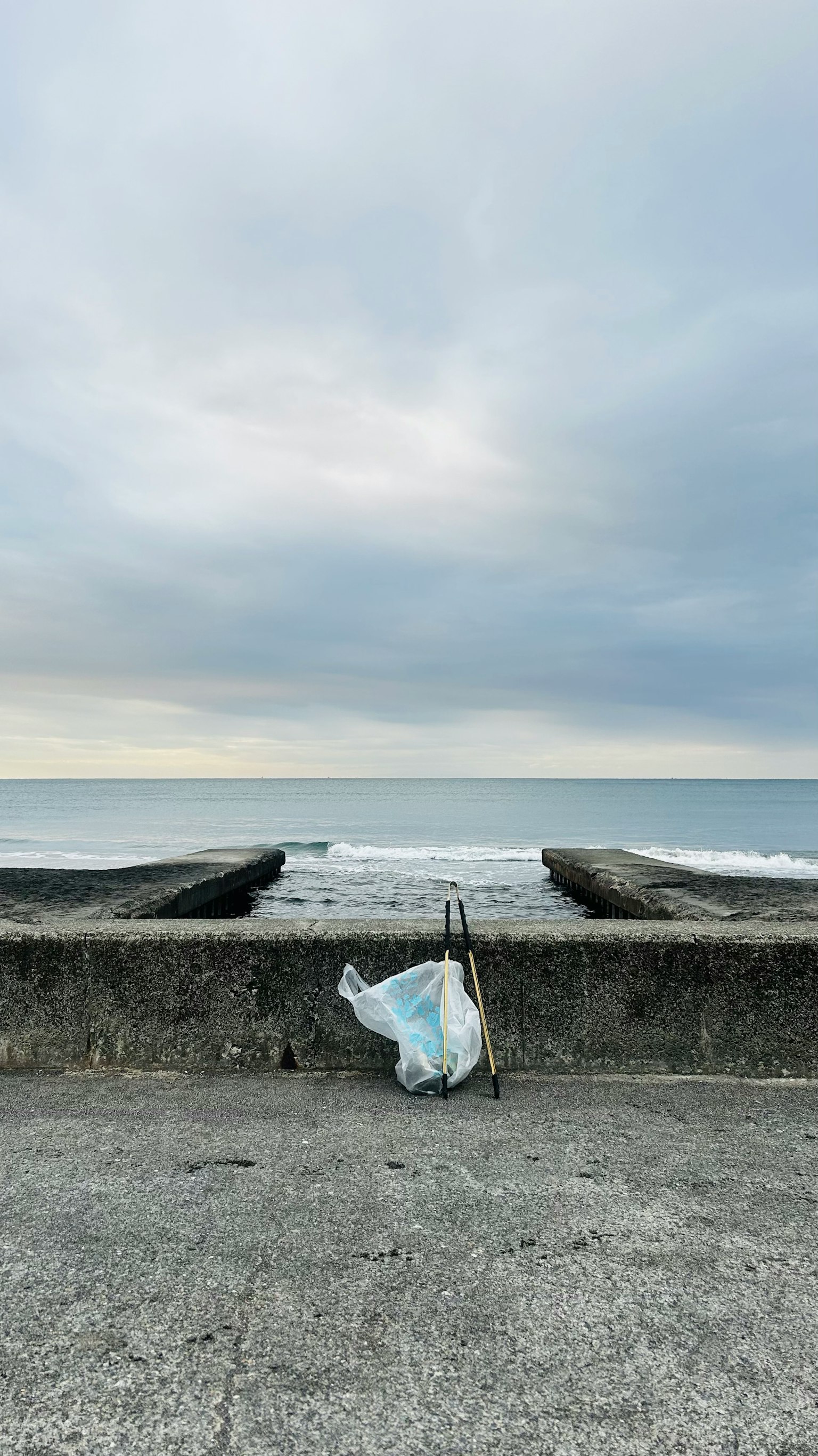 A white plastic bag placed on a concrete seawall facing the ocean