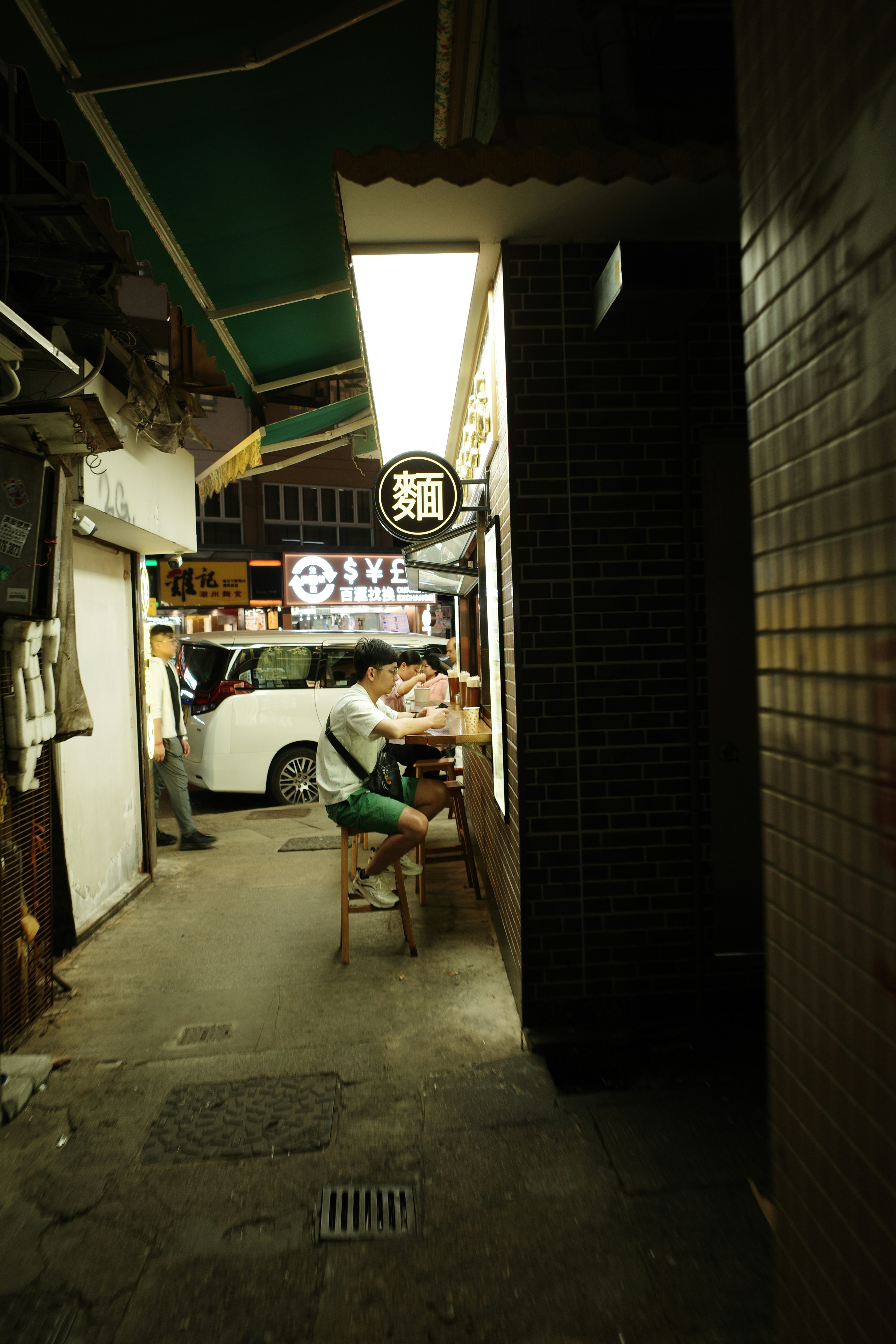 暗い路地の小さな麺店の看板と椅子に座る人