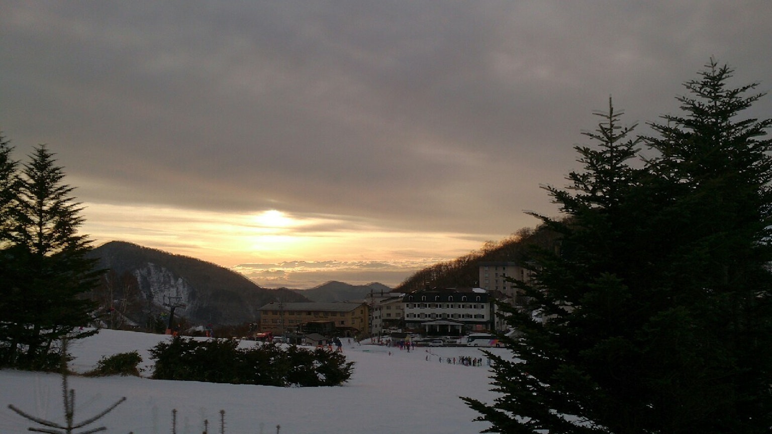 Snow-covered landscape with mountains and a setting sun