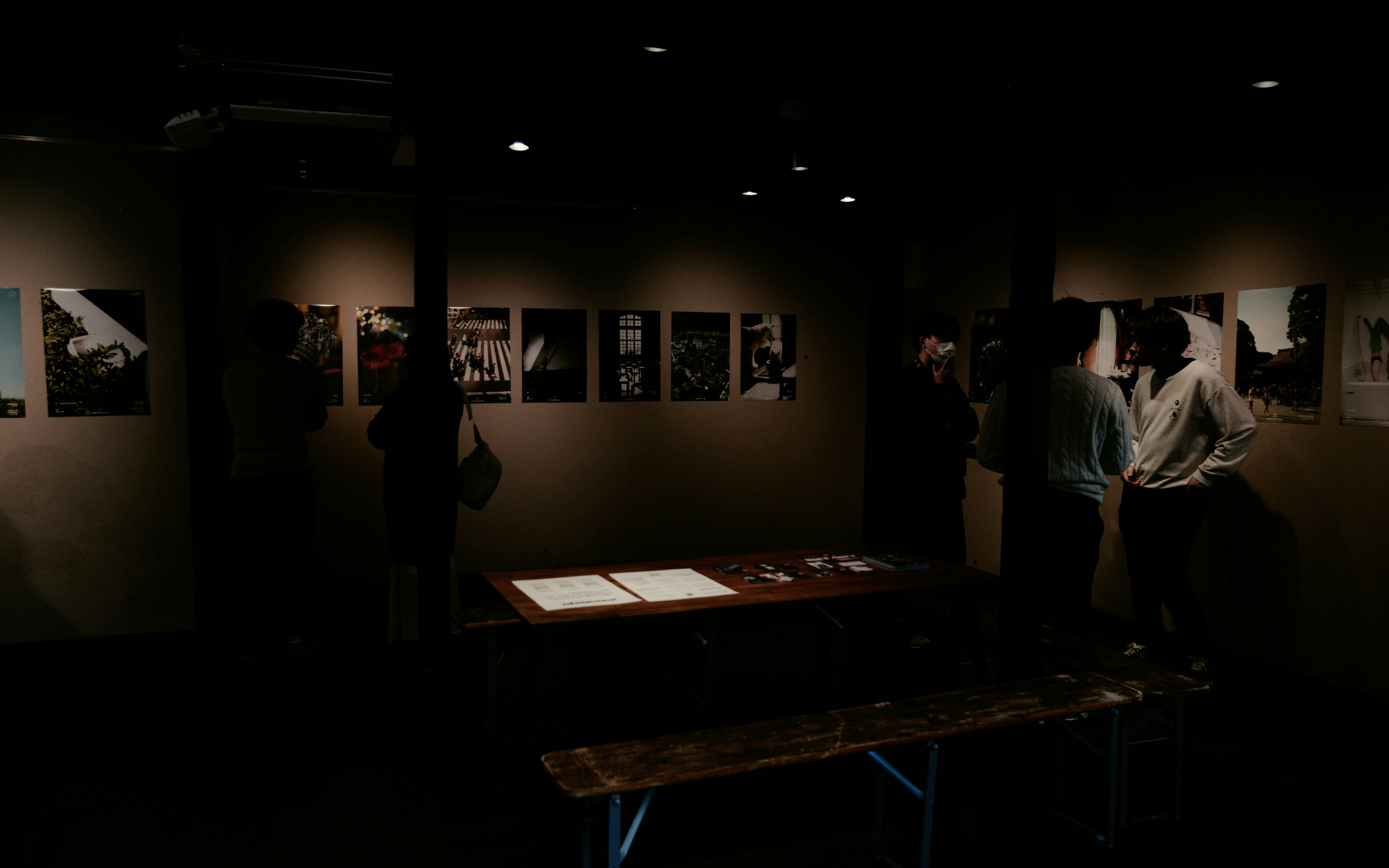 展示会場の薄暗いギャラリー空間で人が作品を鑑賞する様子