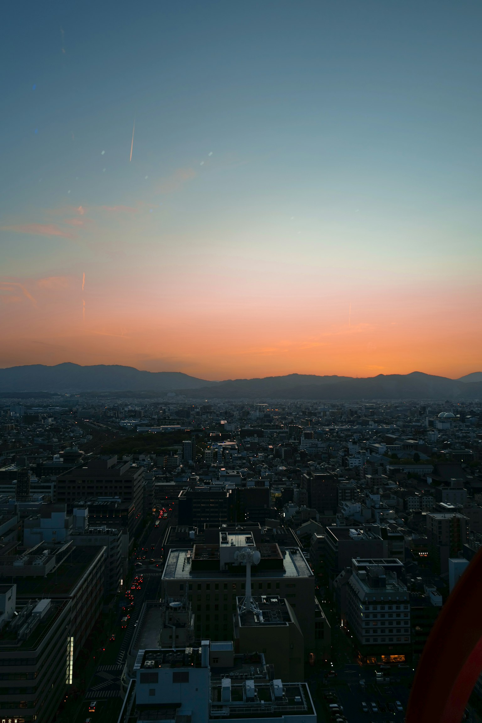 Stadtlandschaft bei Sonnenuntergang mit buntem Himmel und fernen Bergen