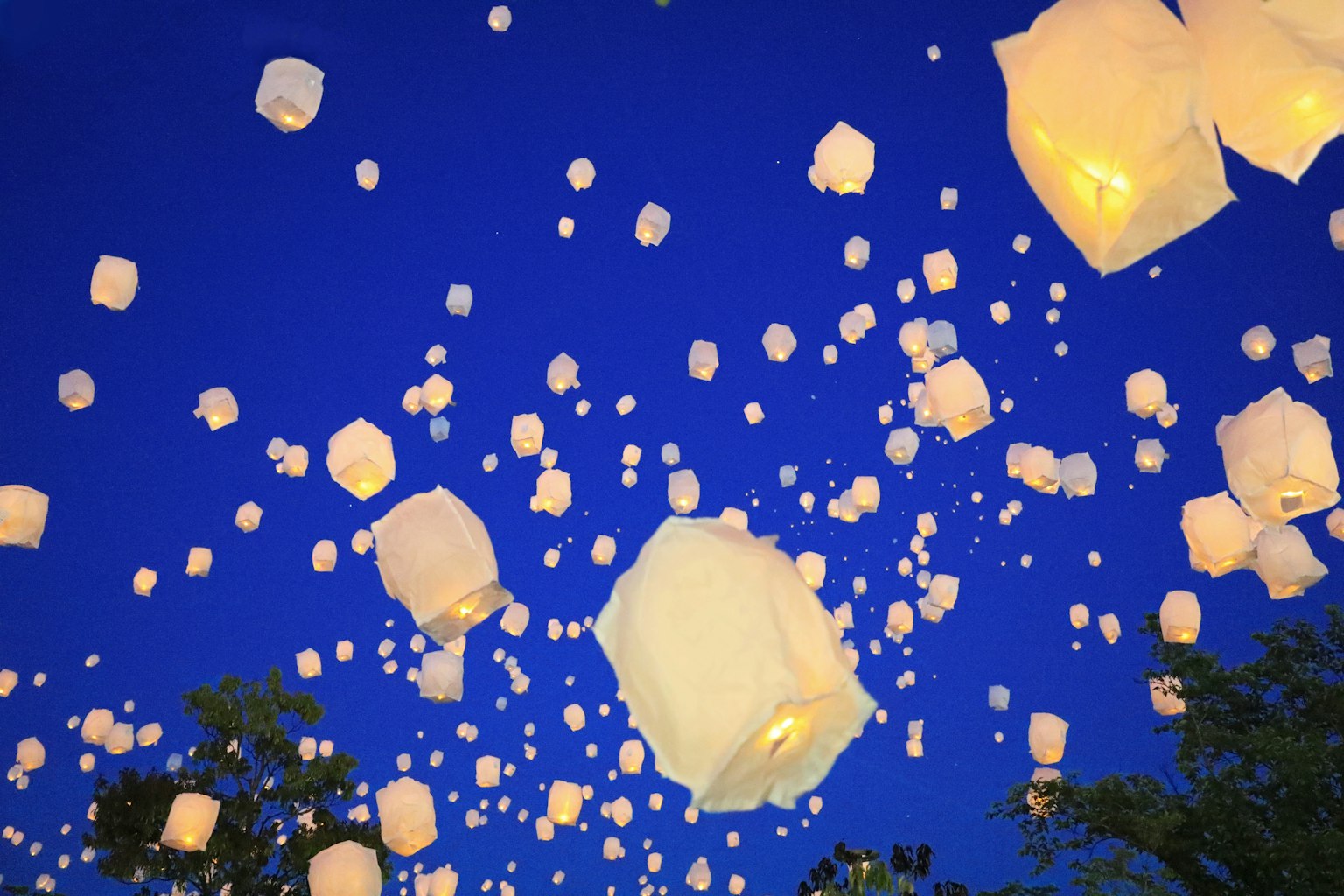 Innombrables lanternes blanches flottant dans un ciel bleu