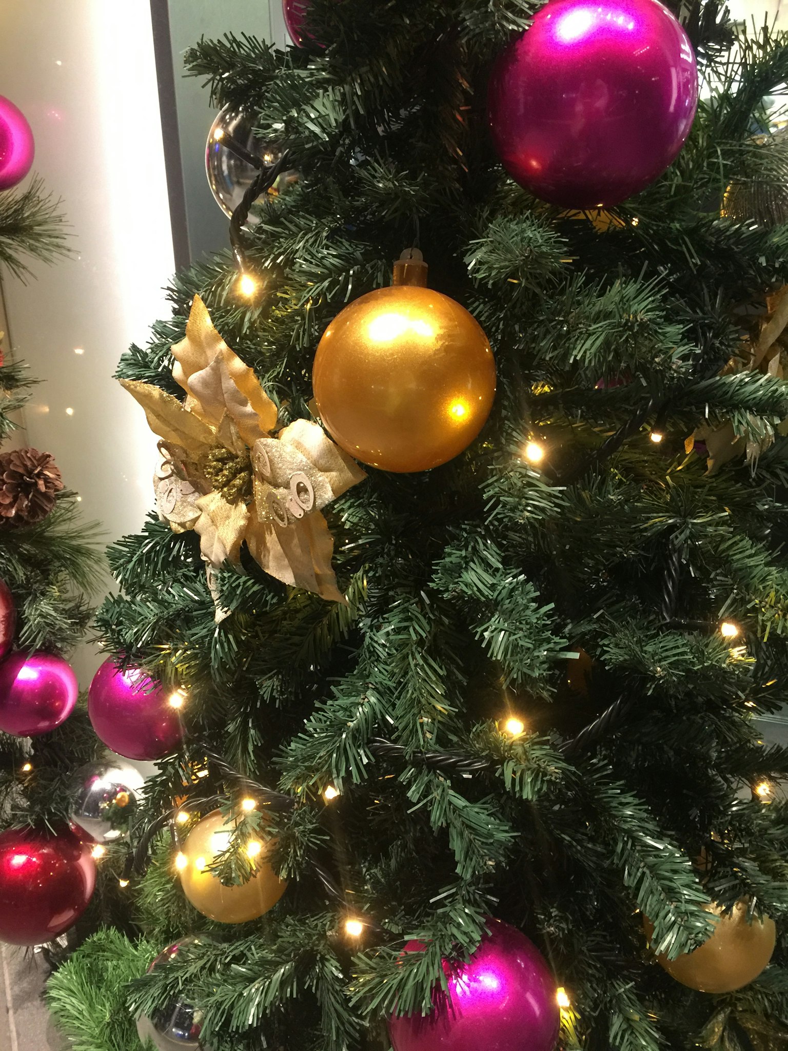 Christmas tree adorned with pink and gold ornaments and glowing lights