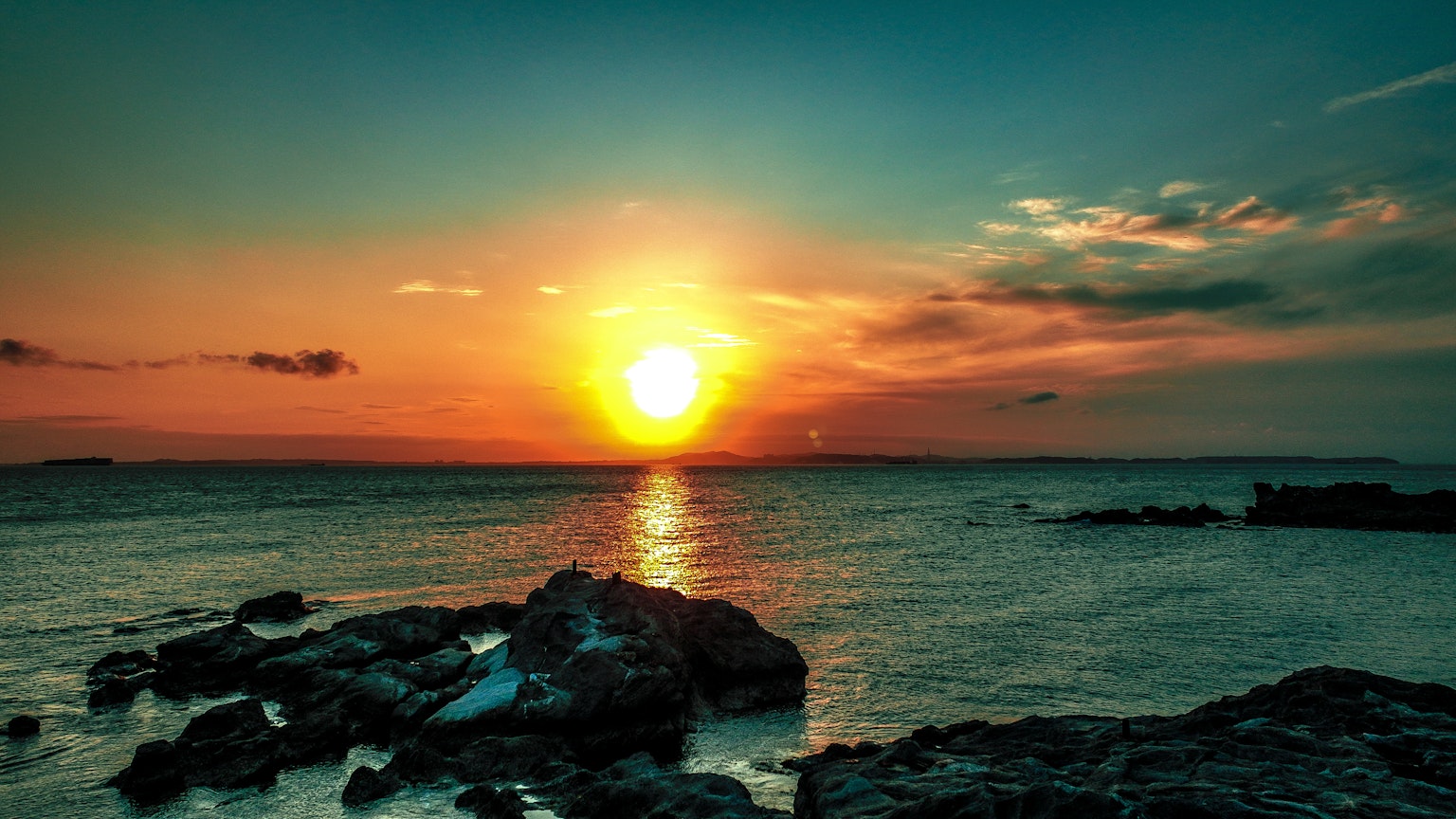 Coucher de soleil sur l'océan avec des rochers et des reflets dans l'eau