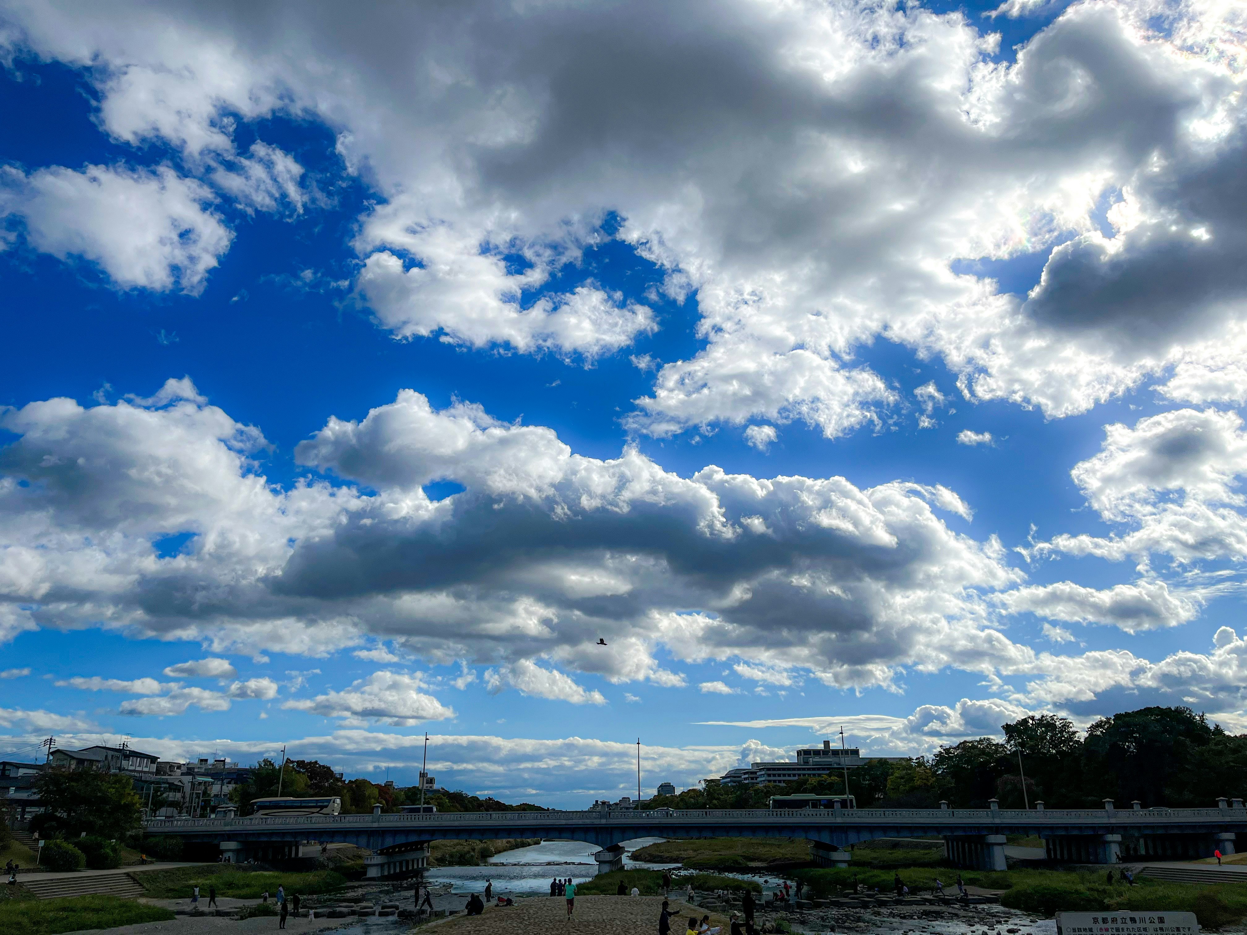 流れる雲の広がる空と川沿いの景色